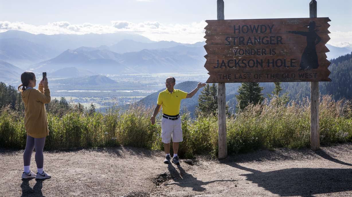 Kao Vang, of Detroit, Mich., photographs her husband, Jeffery, at the top of Teton Pass in Wilson, Wyo., on Aug. 23, 2023. A new Wyoming program aimed at improving safety on Teton Pass took effect Thursday for motorists.