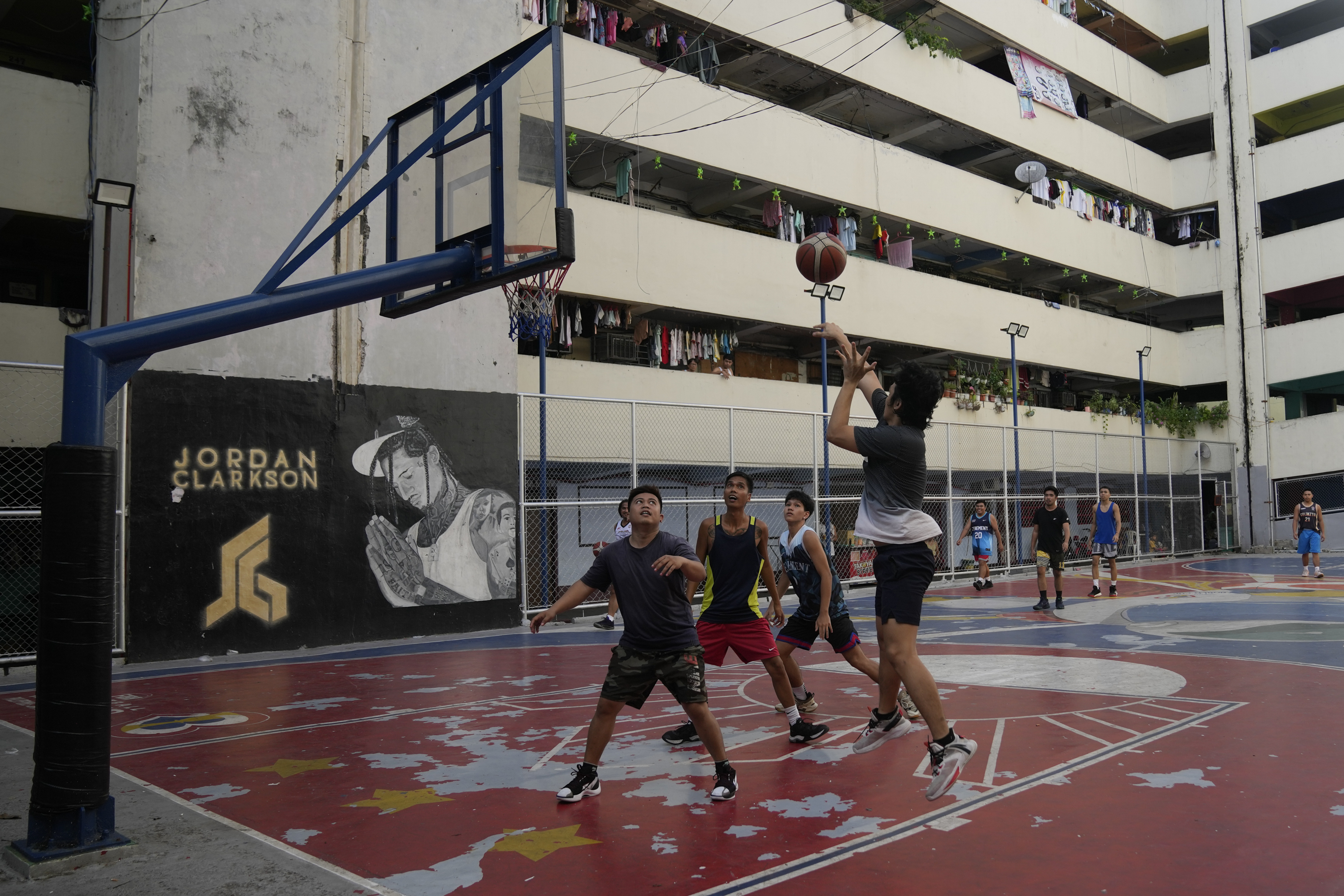People play basketball in front of a wall painted with Jordan Clarkson, a Filipino-American NBA player for the Utah Jazz, on a FIBA Basketball World Cup themed court Thursday, Aug. 17, 2023, in Taguig city Philippines.