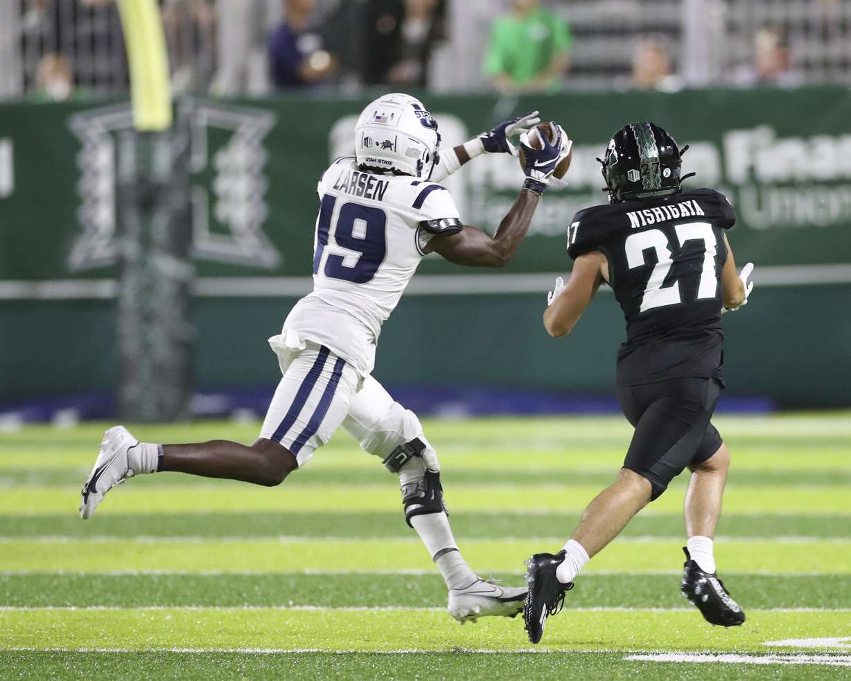 Utah State safety Ike Larsen (19) makes an interception over Hawaii wide receiver Koali Nishigaya (27) during the fourth quarter of an NCAA college football game, Saturday, Nov. 12, 2022, in Honolulu.