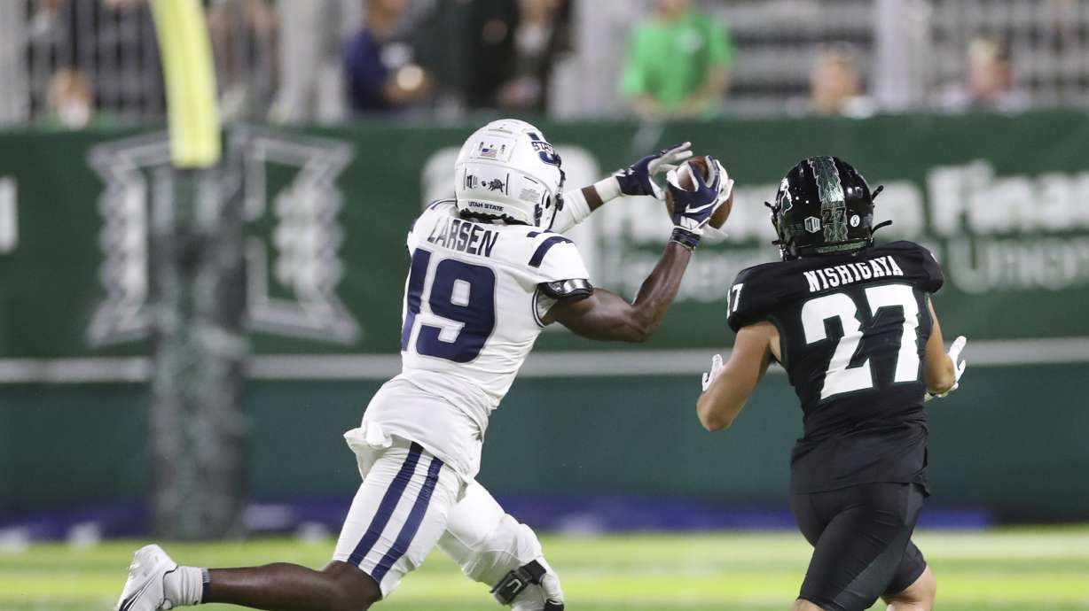 Utah State safety Ike Larsen (19) makes an interception over Hawaii wide receiver Koali Nishigaya (27) during the fourth quarter of an NCAA college football game, Saturday, Nov. 12, 2022, in Honolulu.