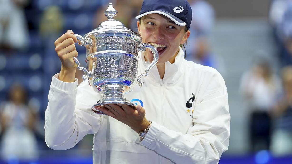 FILE - Iga Swiatek, of Poland, poses with the championship trophy after defeating Ons Jabeur, of Tunisia, in the women's singles final of the U.S. Open tennis championships, Saturday, Sept. 10, 2022, in New York. Tennis is in a state of transition as the U.S. Open is set to begin on Aug. 28.