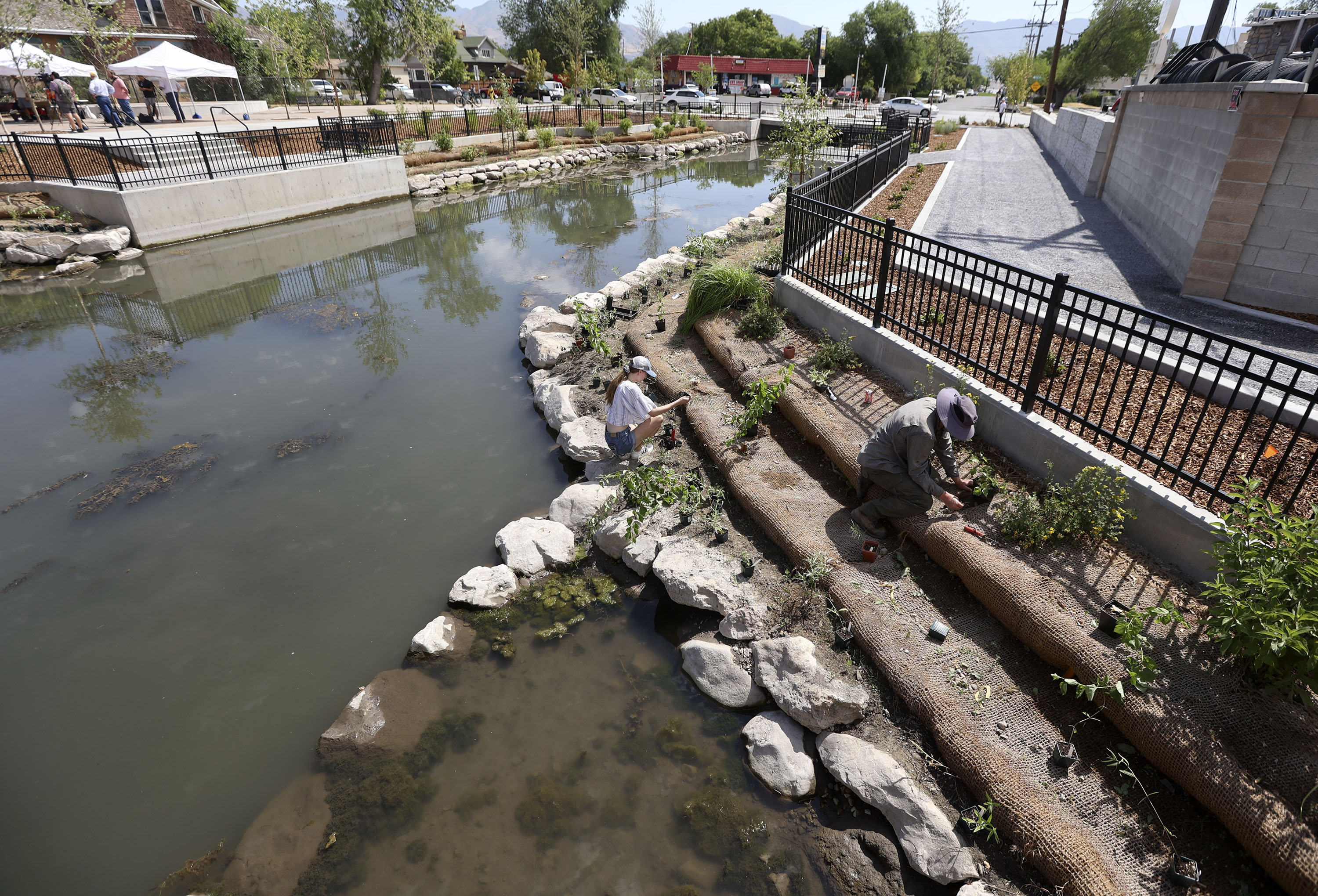 Madeline Houghton, Salt Lake City Trails and Natural Lands botanist intern, and Blake Wellard, Salt Lake City Trails and Natural Lands botanist, plant native shrubs, trees at Three Creeks Confluence Park in Salt Lake City on July 7, 2021.