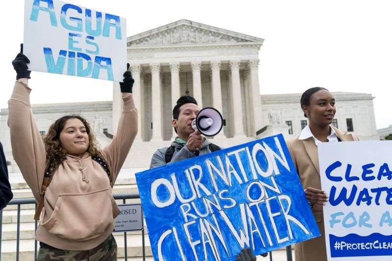Bethsaida Sigaran, left, of Baltimore, her brother Jaime Sigaran, with American Rivers, and Thea Louis, with Clean Water Action, join supporters of the Clean Water Act as they demonstrate outside the Supreme Court, Oct. 3, 2022, in Washington.