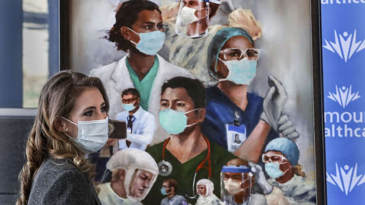 Utah artist Heather Olsen stands with her painting, “Together We Can Do This,” at the Intermountain Transformation Center in Murray on April 5, 2021. Olsen painted the work to honor Utah caregivers for their dedication, commitment and heroics.
