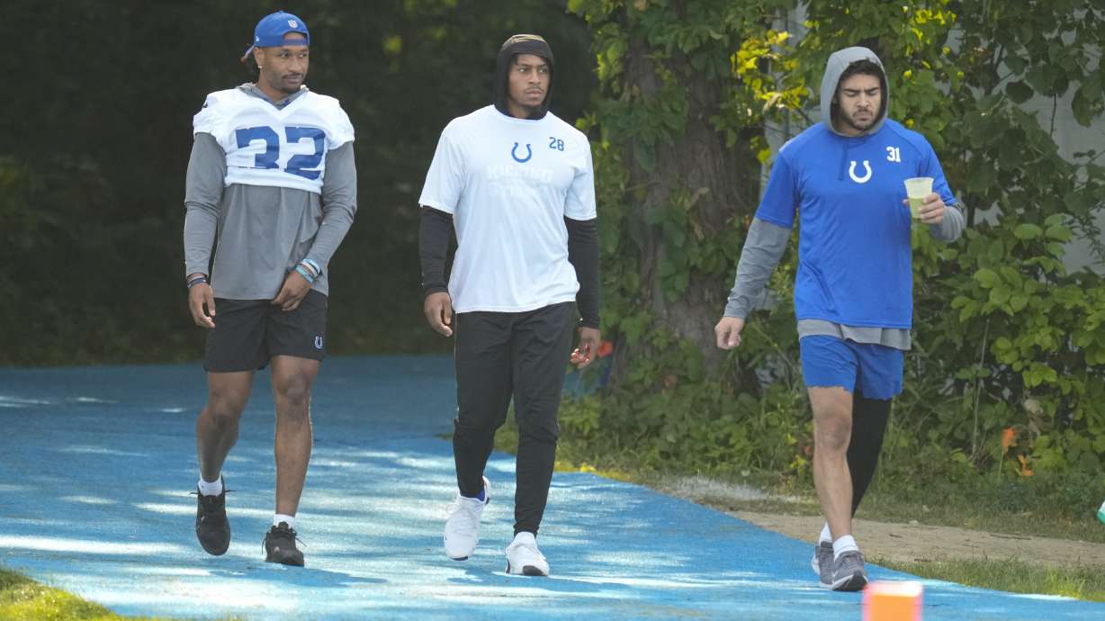 Indianapolis Colts players not participating in practice, left to right, safety Julian Blackmon, running back Jonathan Taylor and safety Daniel Scott walk to the field during practice at the NFL team's football training camp in Westfield, Ind., Tuesday, Aug. 1, 2023.
