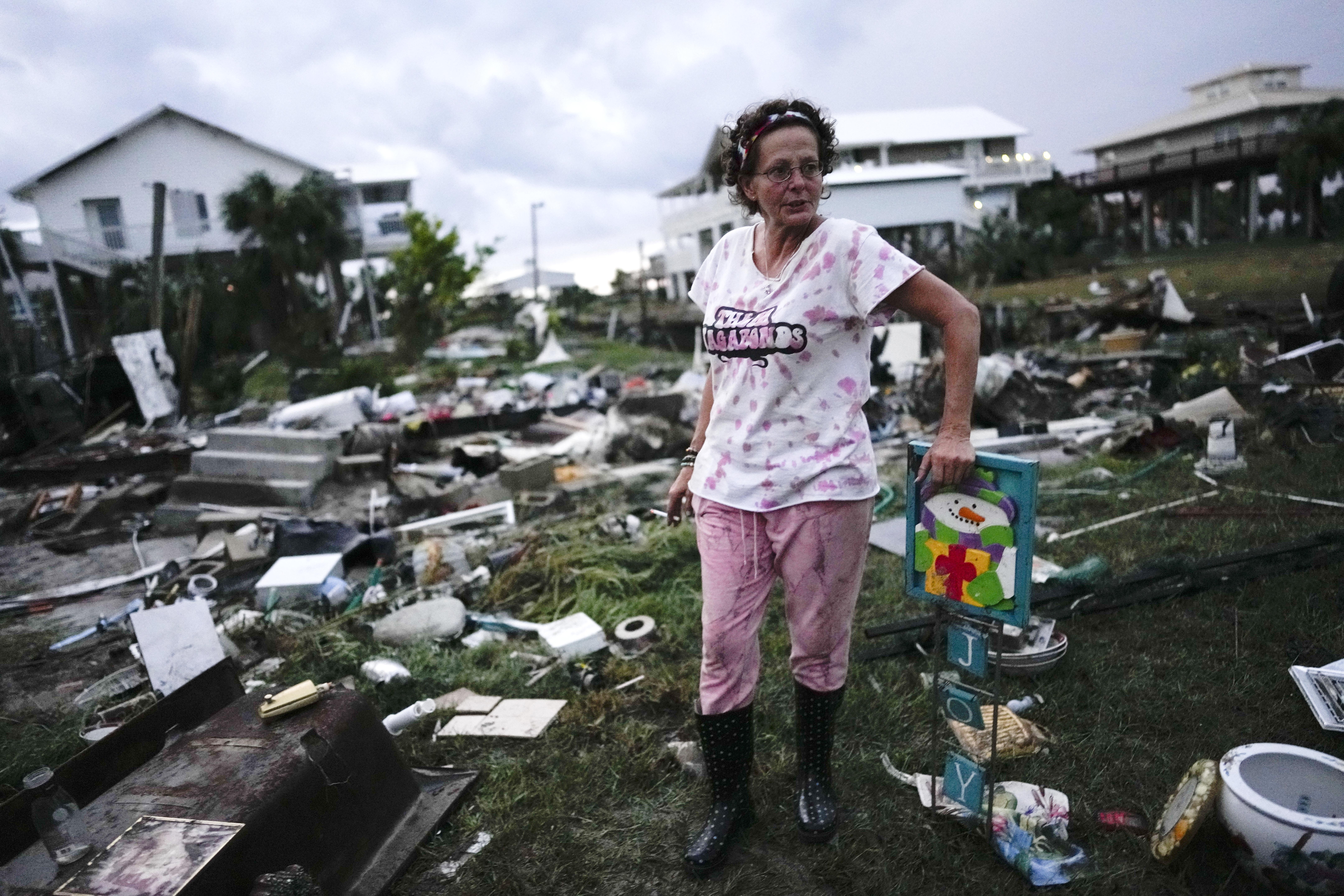 Jewell Baggett stands beside a Christmas decoration she recovered from the wreckage of her mother’s home, as she searches for anything salvageable from the trailer home her grandfather had acquired in 1973 in Horseshoe Beach, Fla., Wednesday.