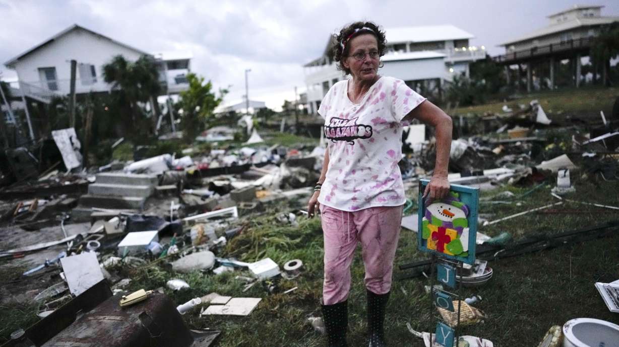 Jewell Baggett stands beside a Christmas decoration she recovered from the wreckage of her mother’s home, as she searches for anything salvageable from the trailer home her grandfather had acquired in 1973 in Horseshoe Beach, Fla., Wednesday.