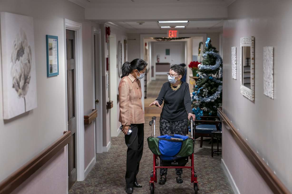 Tina Sandri, CEO of Forest Hills of DC senior living facility, left, helps resident Courty Andrews back to her room, Dec. 8, 2022, in Washington. The federal government will, for the first time, dictate staffing levels at nursing homes, the Biden administration said Friday responding to systemic problems bared by mass COVID deaths.