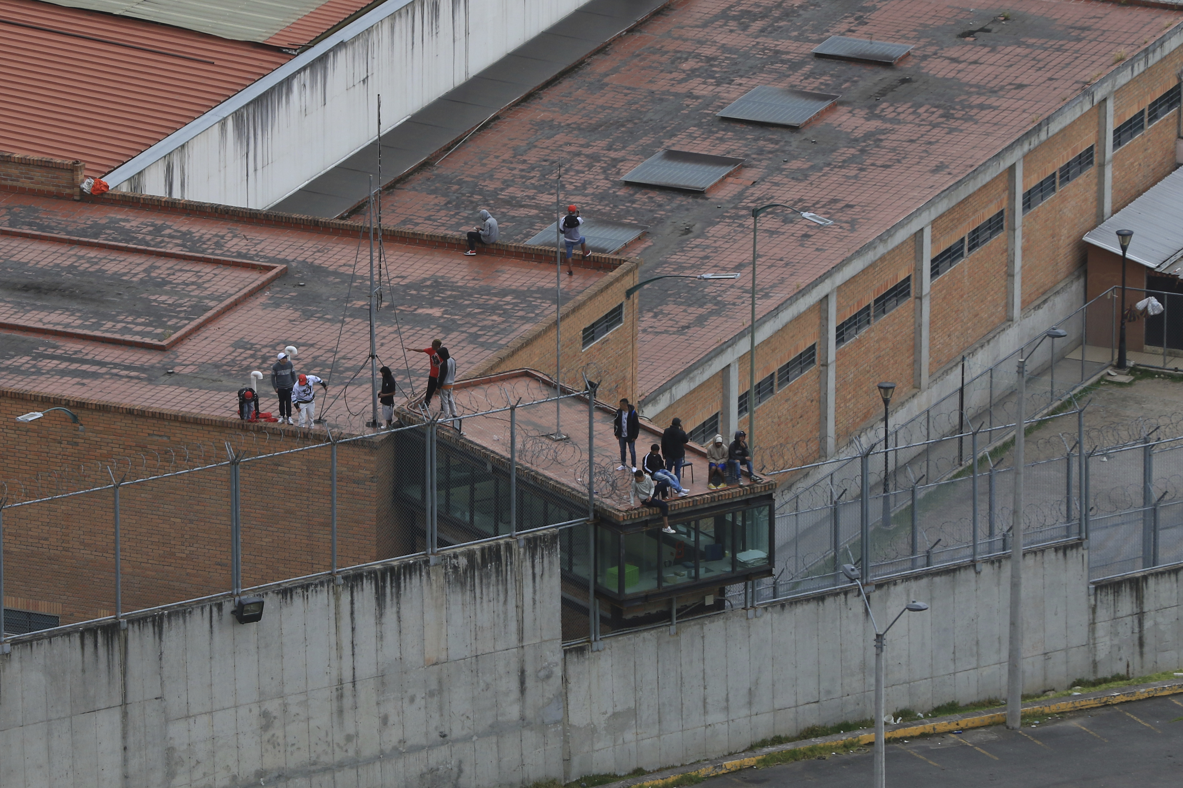 Prisoners stand on the roof of the Turi jail where dozens of prison guards and police officers have been kidnapped by the inmates, in Cuenca, Ecuador, on Thursday. In the last 24 hours, Ecuador has been rocked by the explosions of four car bombs and the hostage-taking of more than 50 law enforcement officers inside various detention facilities.