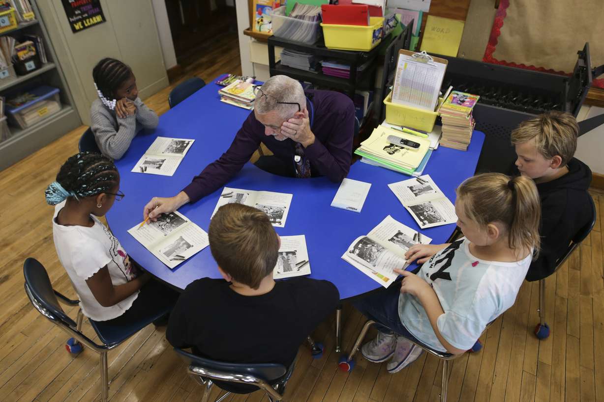 Richard Evans, a teacher at Hyde Park Elementary School, helps a student sound out a word during a reading circle in class on Oct. 20, 2022, in Niagara Falls, N.Y. Stuck with distance learning as they began grade school, the kids who are now finishing elementary school were the ones most disrupted by COVID, with alarming delays in their reading ability.