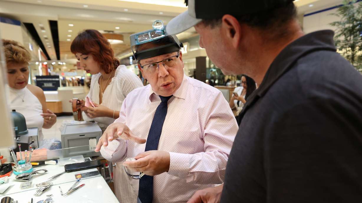 Marcelo Sandivar, certified watch technician and owner of Fashion Watch & Clock, helps a customer at the company’s kiosk in Fashion Place Mall in Murray on Aug. 24. His wife and granddaughter work behind him.
