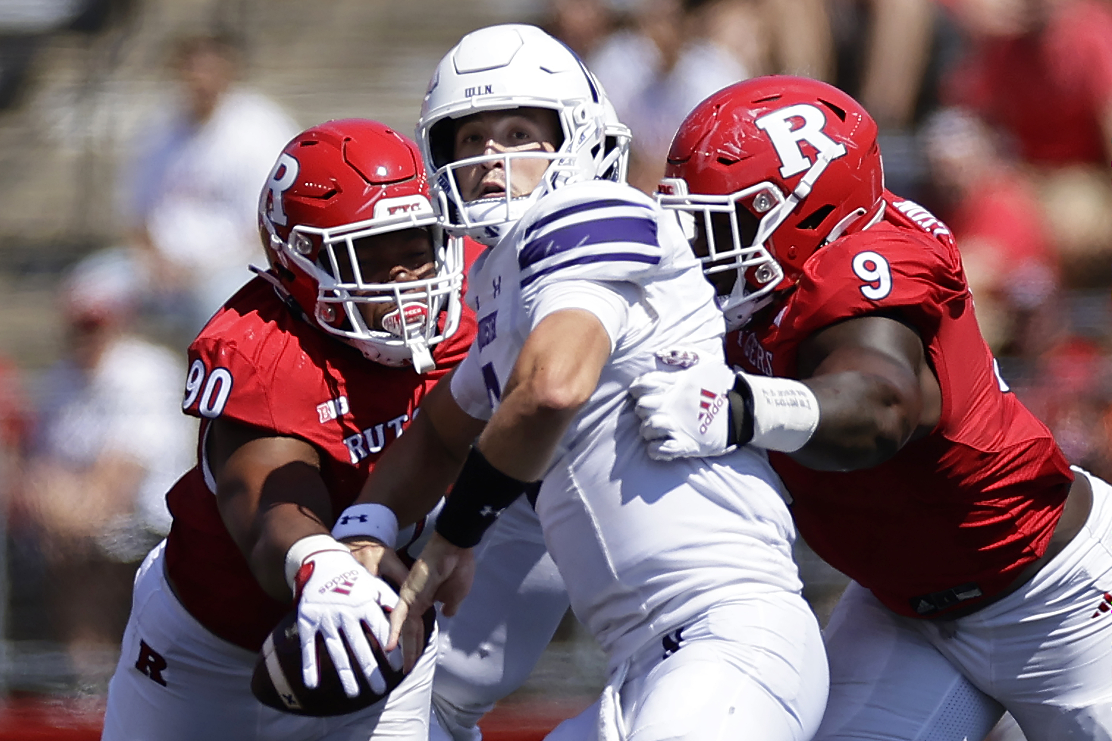 Northwestern quarterback Ben Bryant (2) is pressured by Rutgers defensive lineman Isaiah Iton (9) and has the ball knocked away by Rene Konga (90) during the first half of an NCAA college football game, Sunday, Sept. 3, 2023, in Piscataway, N.J.
