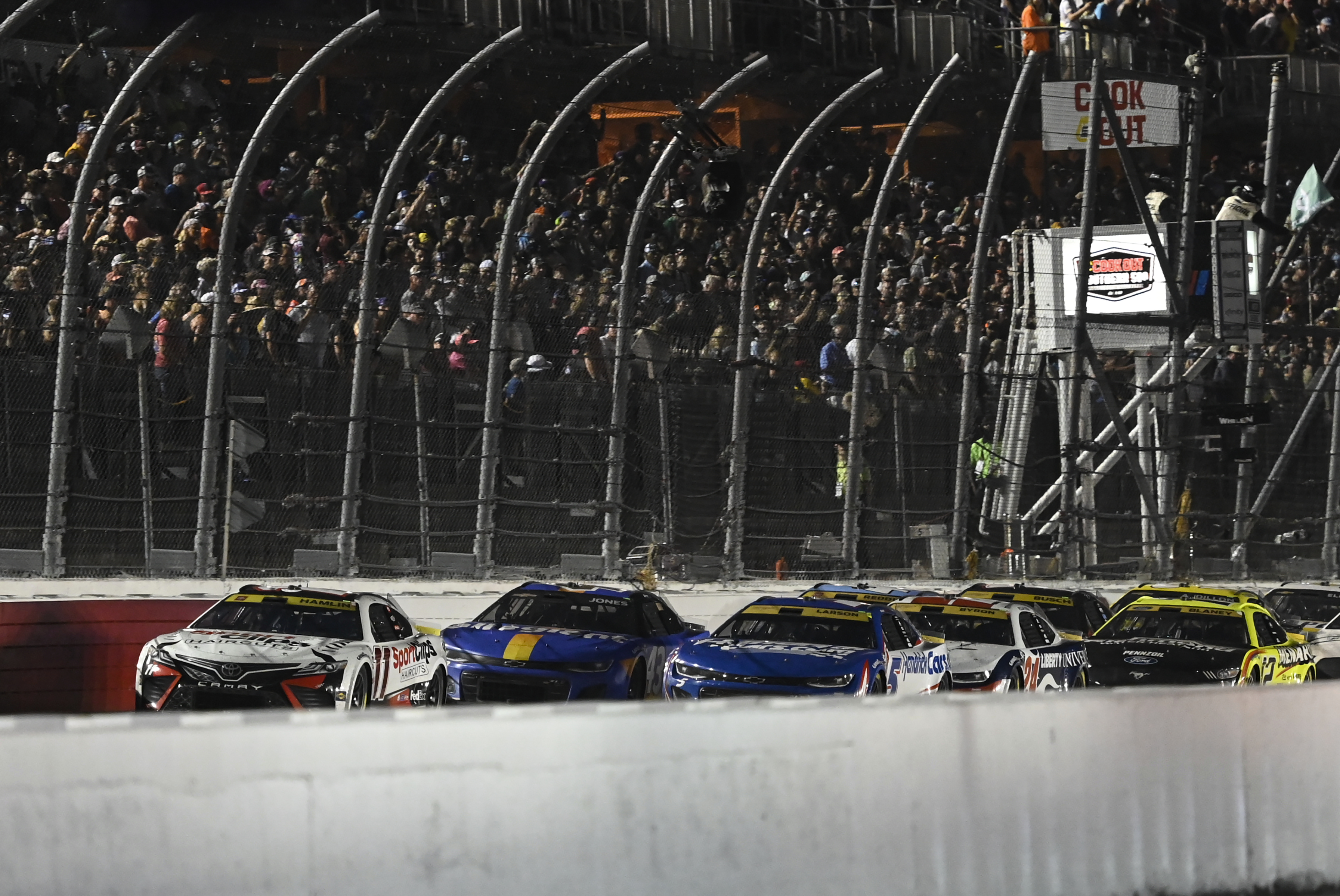 Denny Hamlin (11) leads a pack of cars to a restart during a NASCAR Cup Series auto race at Darlington Raceway, Sunday, Sept. 3, 2023, in Darlington, S.C.