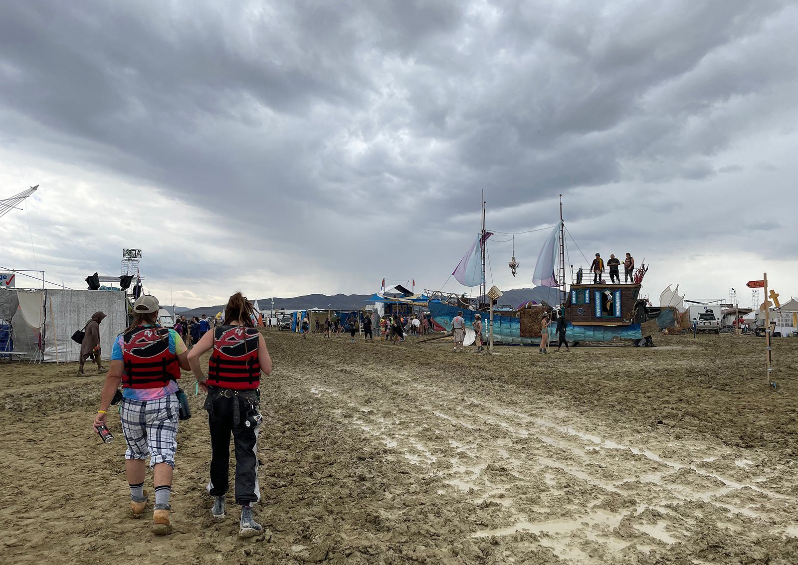 Attendees walk through a muddy desert plain on Saturday at the Burning Man festival site in Nevada.