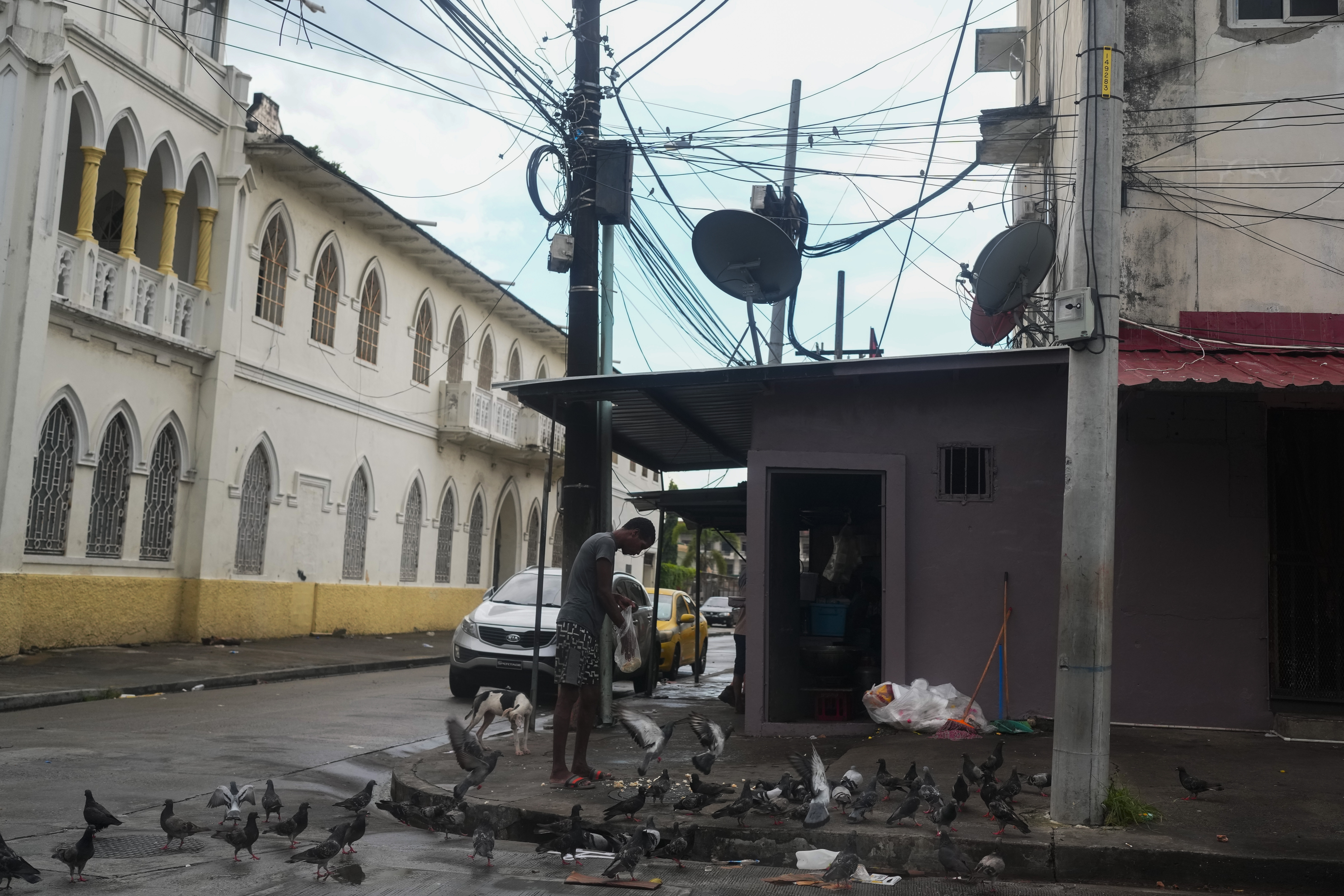 A man feeds pigeons on a street where Gilberto Hernandez, a member of Panama's national soccer team, was shot and killed in Colon, Panama, Monday, Sept. 4, 2023. Hernández was the second member of the national team killed in Colon in the past six years. 