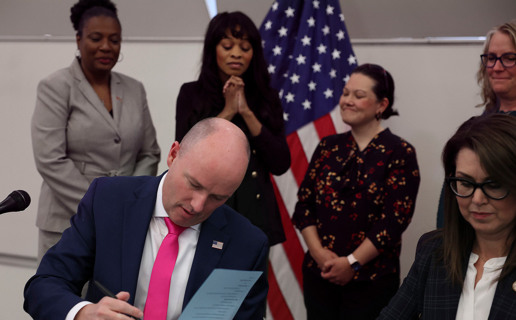 Brittany Tichenor-Cox, mother of  Isabella “Izzy” Tichenor, second from left, watches on April 14, 2022, as Gov. Spencer Cox signs HB428, also known as Izzy’s bill, is designed to address bullying and harassment in schools. According to a new survey, 40% of kids have been bullied in the past year. 
