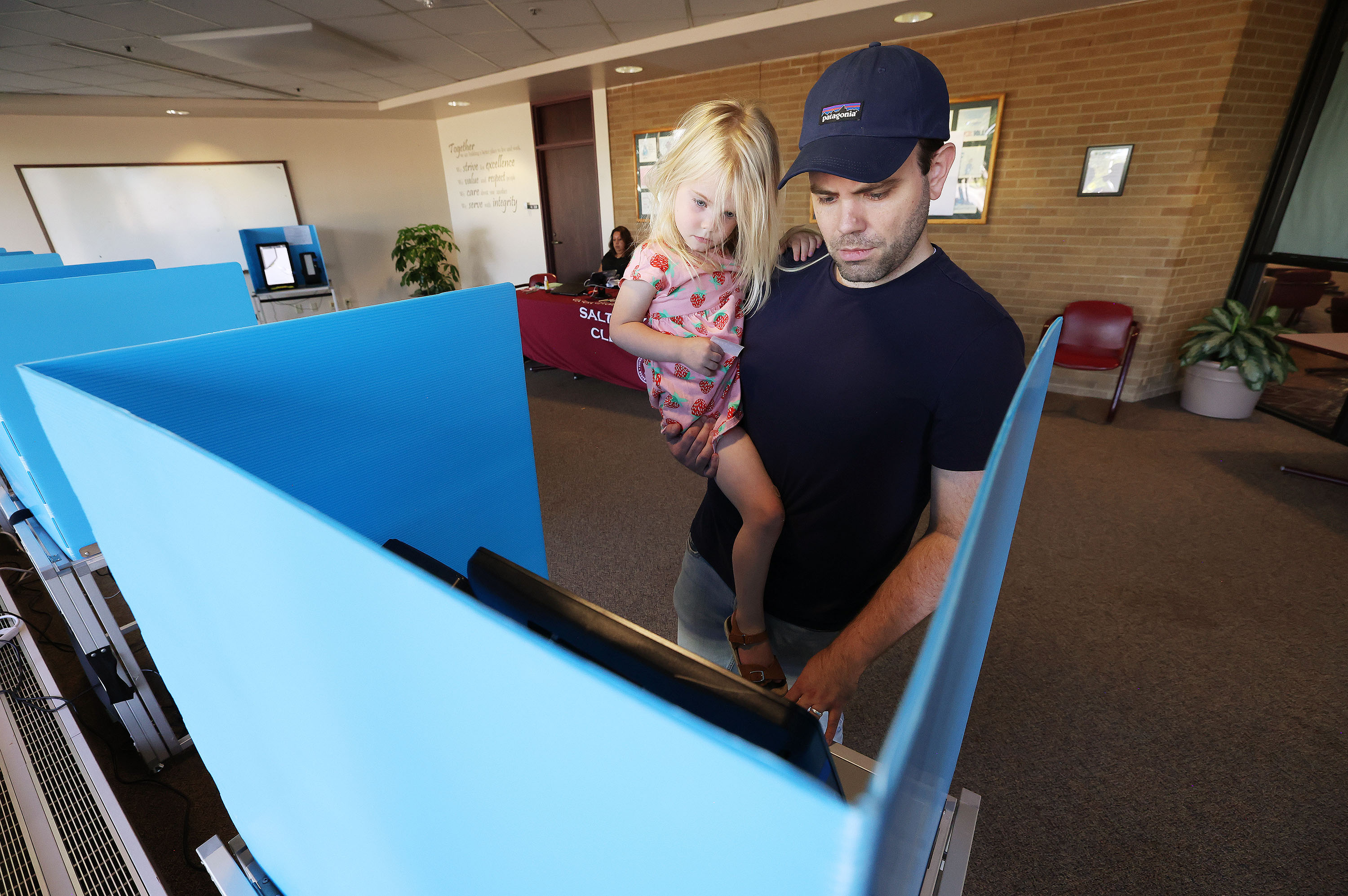 Andrew Roth holds his daughter Maggie as he casts his ballot during Utah's municipal and primary elections, which include the 2nd Congressional District special primary, at the Salt Lake County Government Center in Salt Lake City on Tuesday.