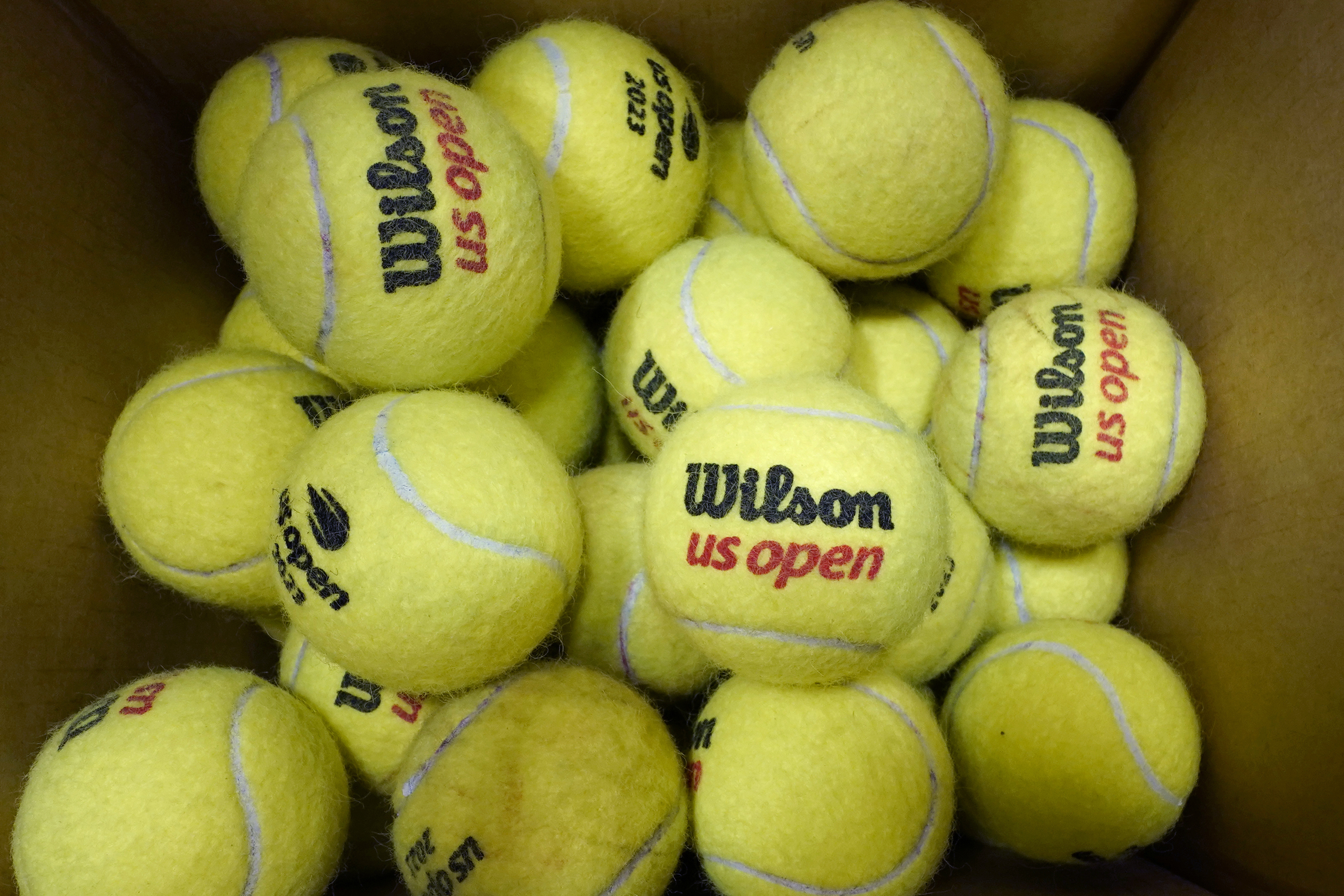 A box of game-used tennis balls rest in a shipping box during the U.S. Open tennis championships, Monday, Sept. 4, 2023, in New York. Because tennis balls are extremely hard to recycle and the industry has yet to develop a ball to make that easier, nearly all of the 330 million balls made worldwide each year eventually get chucked in the garbage, with most ending up in landfills. 