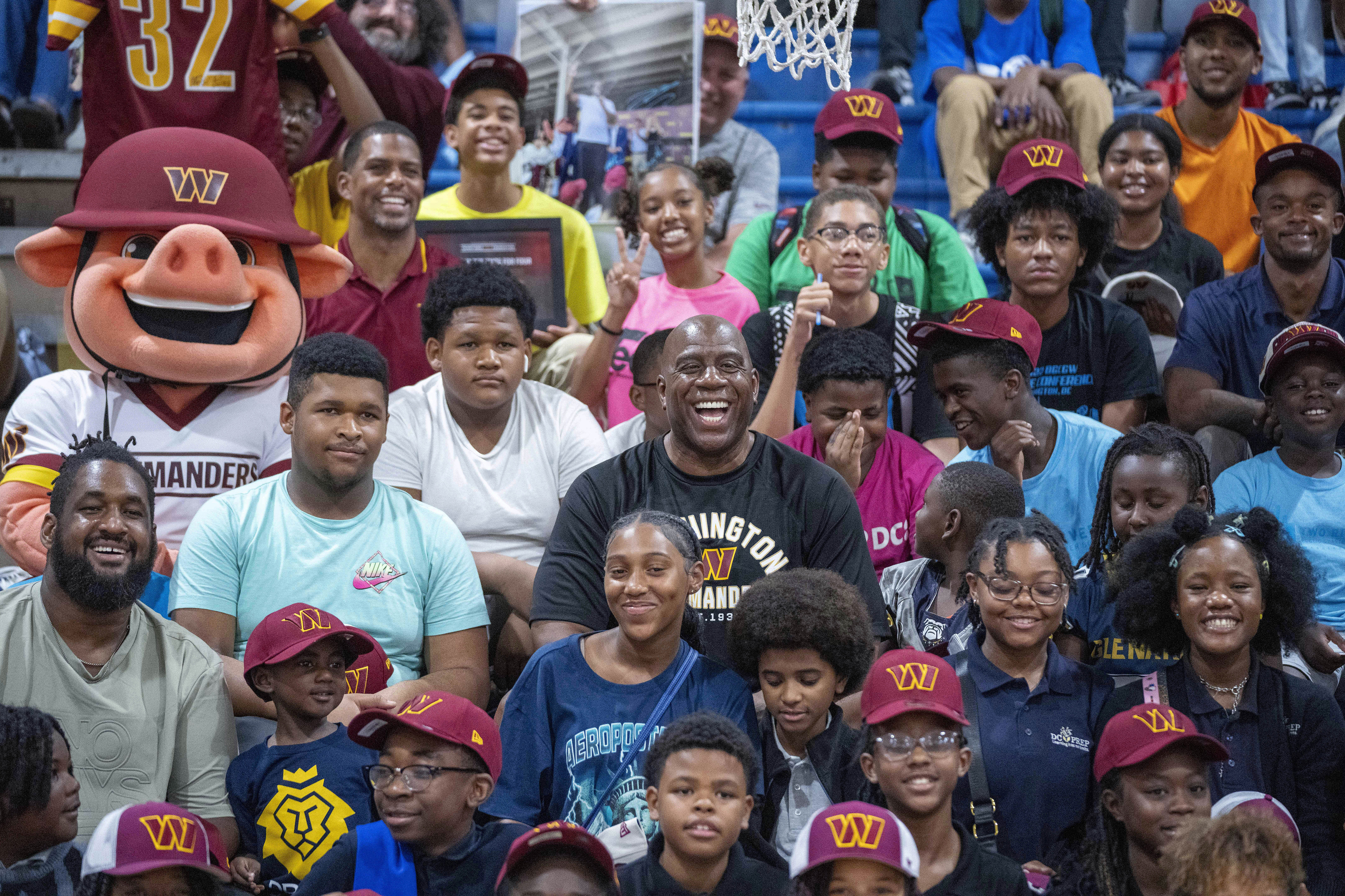 Washington Commanders part-owner Magic Johnson, center, poses for a photo in the stands with children at the Boys and Girls Club of Greater Washington, Thursday, Sept. 7, 2023, in Washington. 