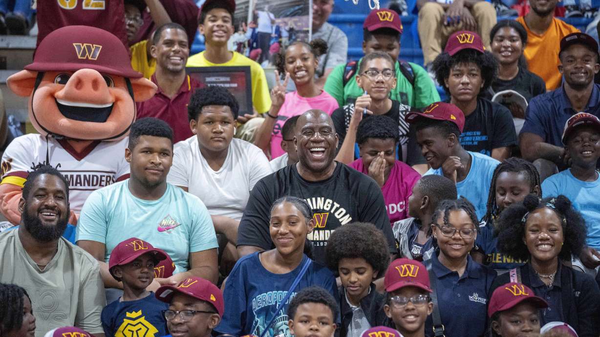 Washington Commanders part-owner Magic Johnson, center, poses for a photo in the stands with children at the Boys and Girls Club of Greater Washington, Thursday, Sept. 7, 2023, in Washington.