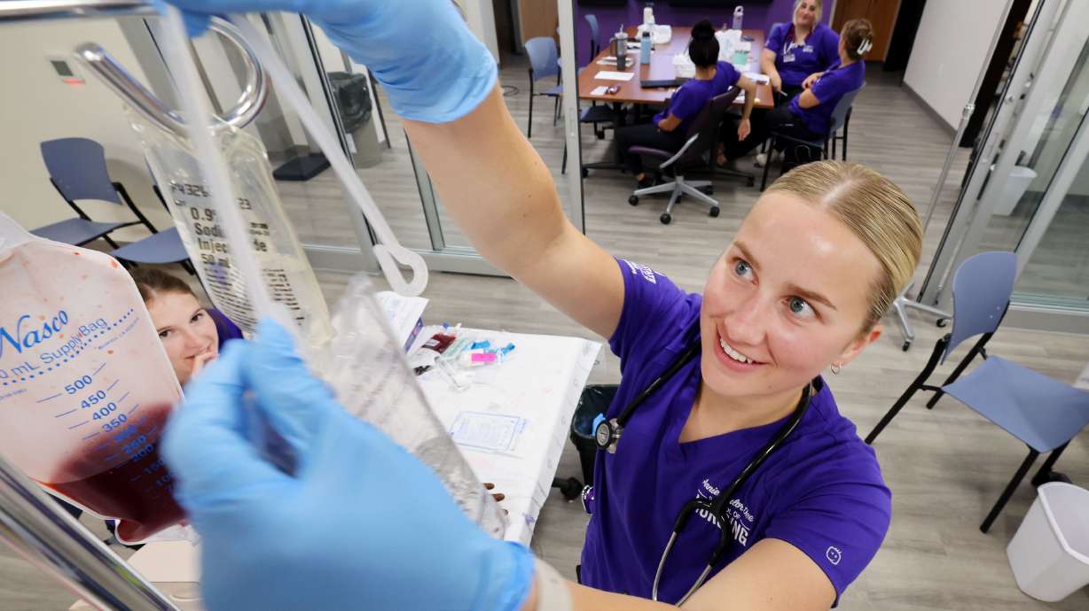Nursing student Kira Fujikawa hangs a fluid bag in the Marriott Health Building at Weber State University in Ogden on Tuesday. A new report affirms the more postsecondary education a person has, the better return on investment.