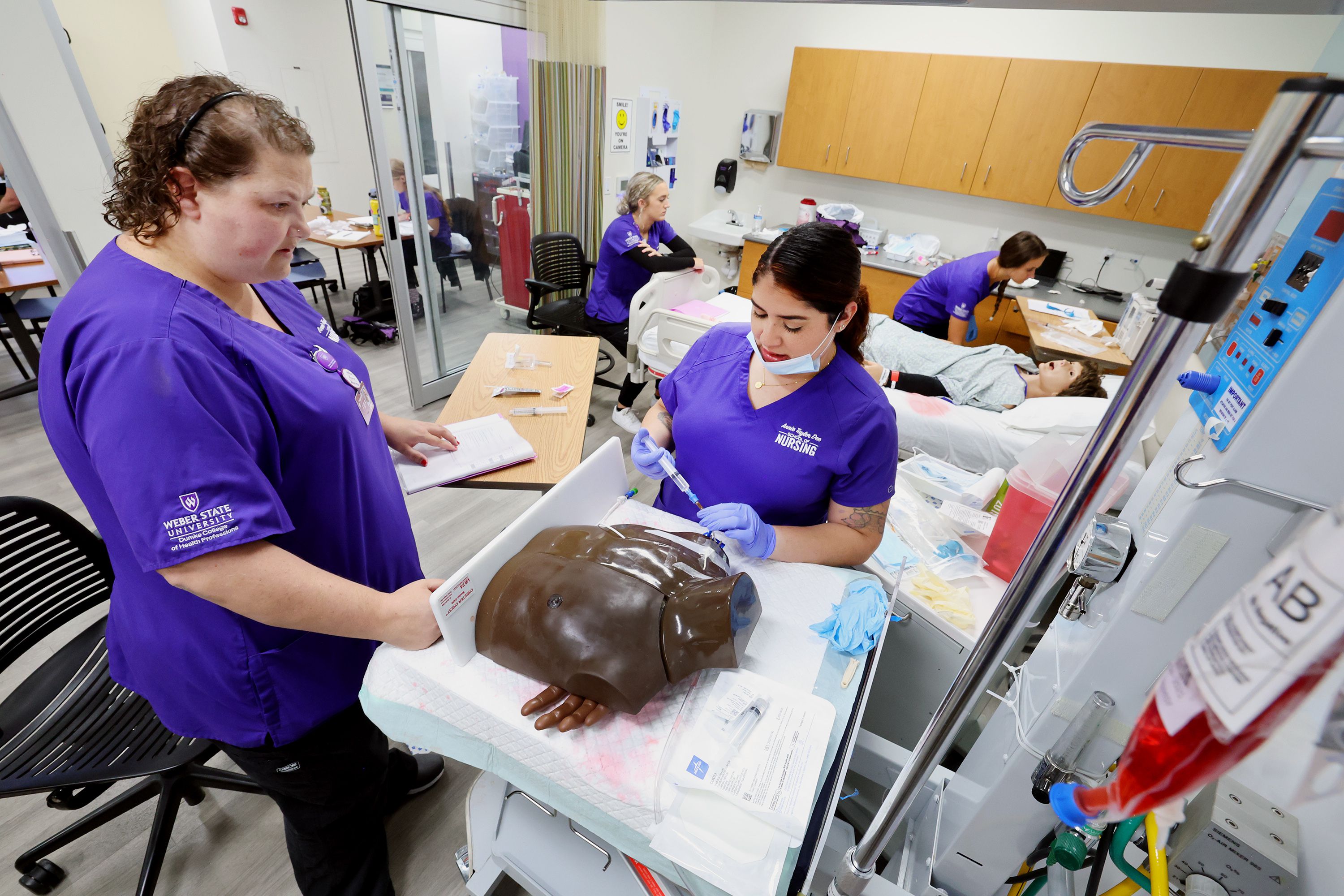 Nursing students Kalley Jaques and Aisha Holts work on a central line change as students work in the simulation lab in the Marriott Health Building at Weber State University in Ogden on Tuesday.