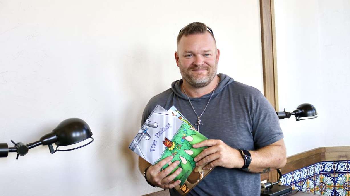 Justin Judkins takes a photo with his children’s books inside Canyon Media in St. George on Aug. 23. “I went from a drug dealer to a book dealer,” Judkins said.