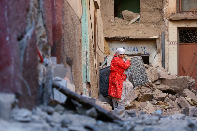A woman carries belongings out of a damaged building, in the aftermath of a deadly earthquake in Moulay Brahim, Morocco, on Sunday.