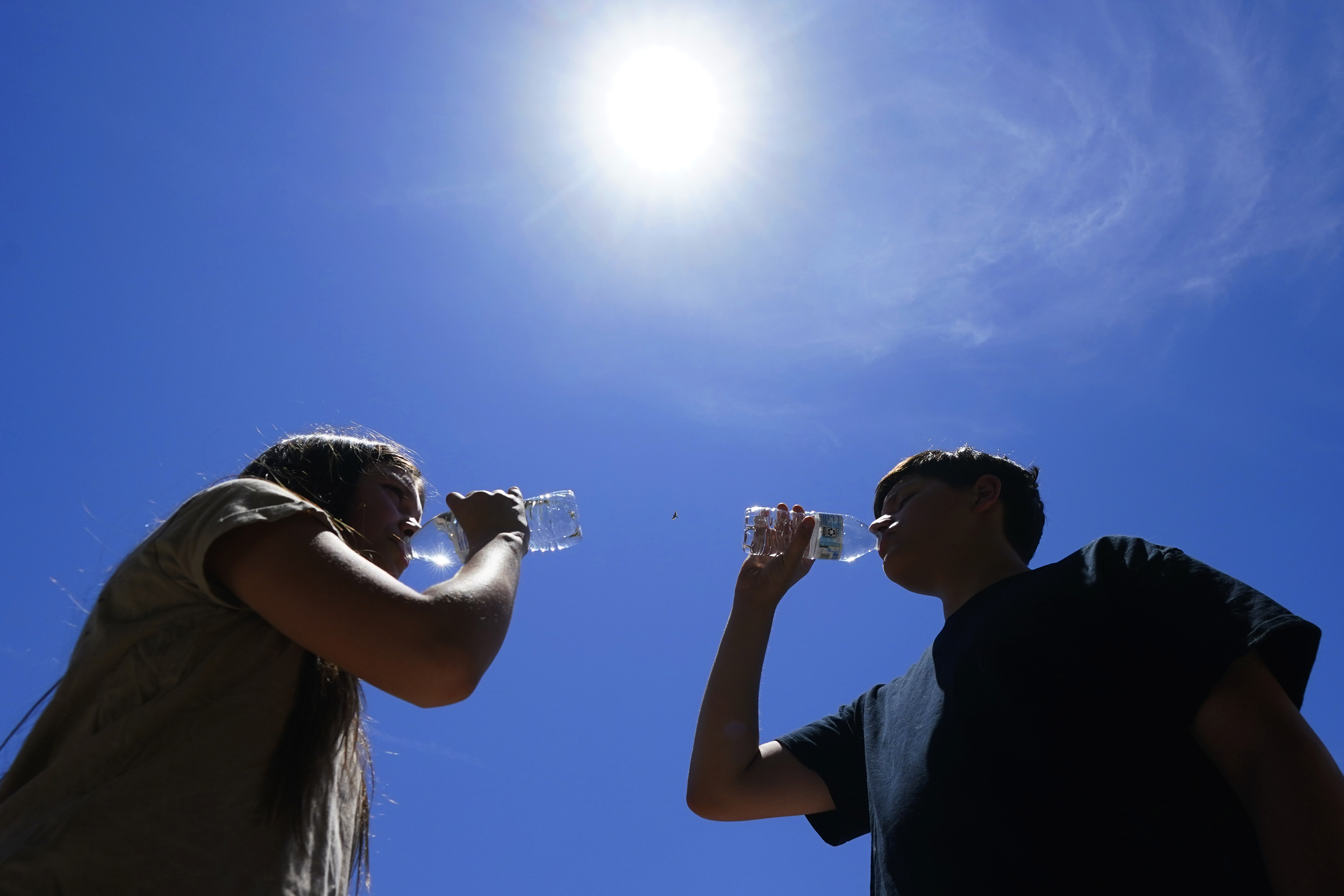 Tony Berastegui Jr., right, and his sister Giselle Berastegui drink water, July 17, in Phoenix. The historic heat wave continues in Phoenix, but the end may finally be in sight for residents of Arizona’s largest city. 