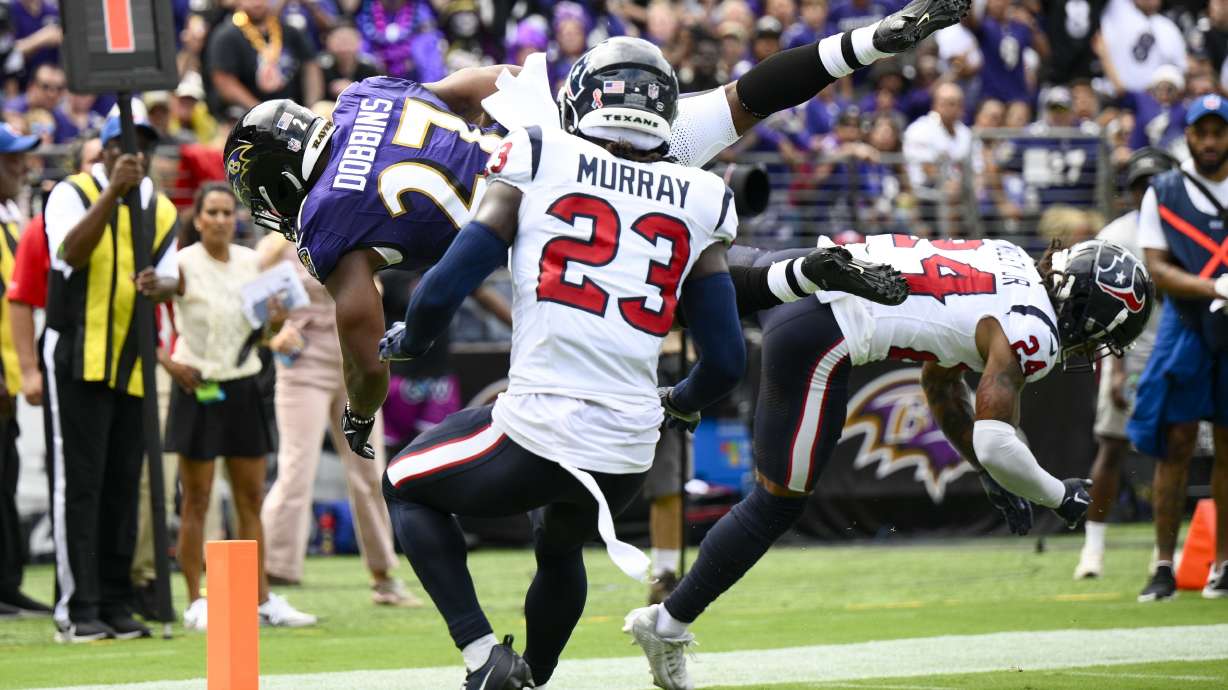 Baltimore Ravens' J.K. Dobbins gets past Houston Texans' Derek Stingley Jr. (24) and Eric Murray (23) for a touchdown during the first half of an NFL football game Sunday, Sept. 10, 2023, in Baltimore.