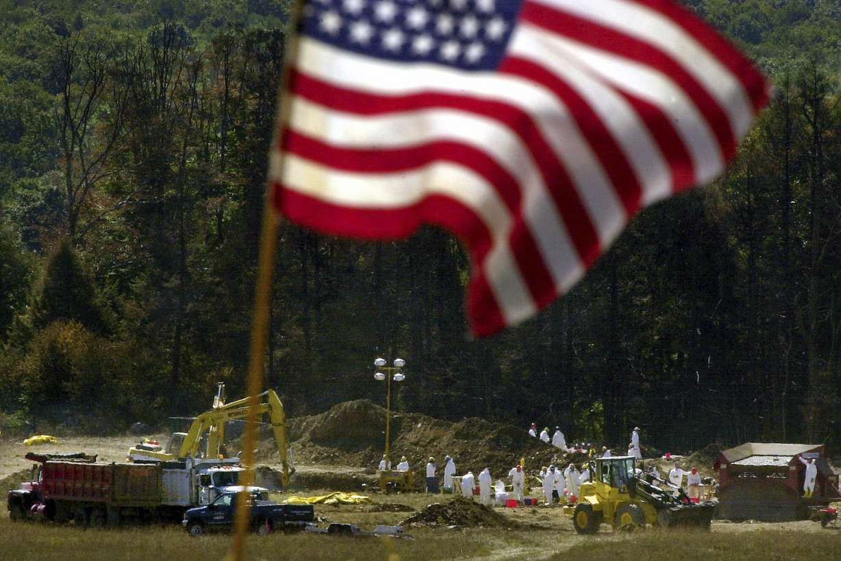 An American flag flies from a makeshift altar overlooking the ongoing investigation of the United Flight 93 crash site, in Shanksville, Pa., Sept. 16, 2001. Americans are looking back on the horror and legacy of 9/11 on Monday.