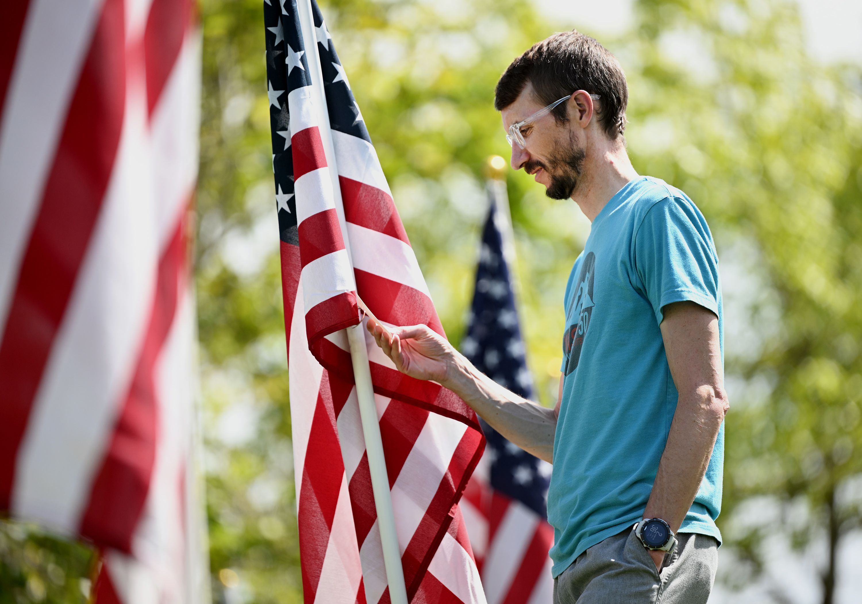 Kris Aubrey reads one of the information cards attached to a flag at the Sandy 9/11 Healing Field on Sunday.
