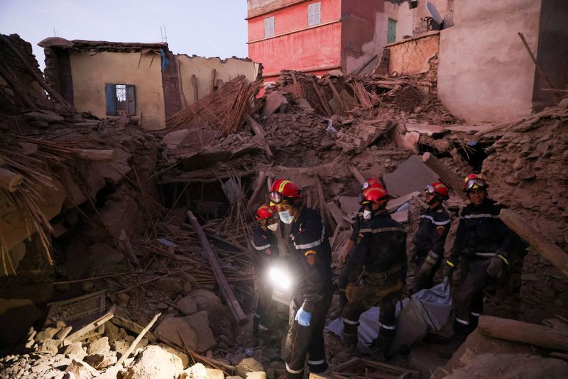 Emergency workers carry a dead body, in the aftermath of a deadly earthquake, in Amizmiz, Morocco, Sunday.