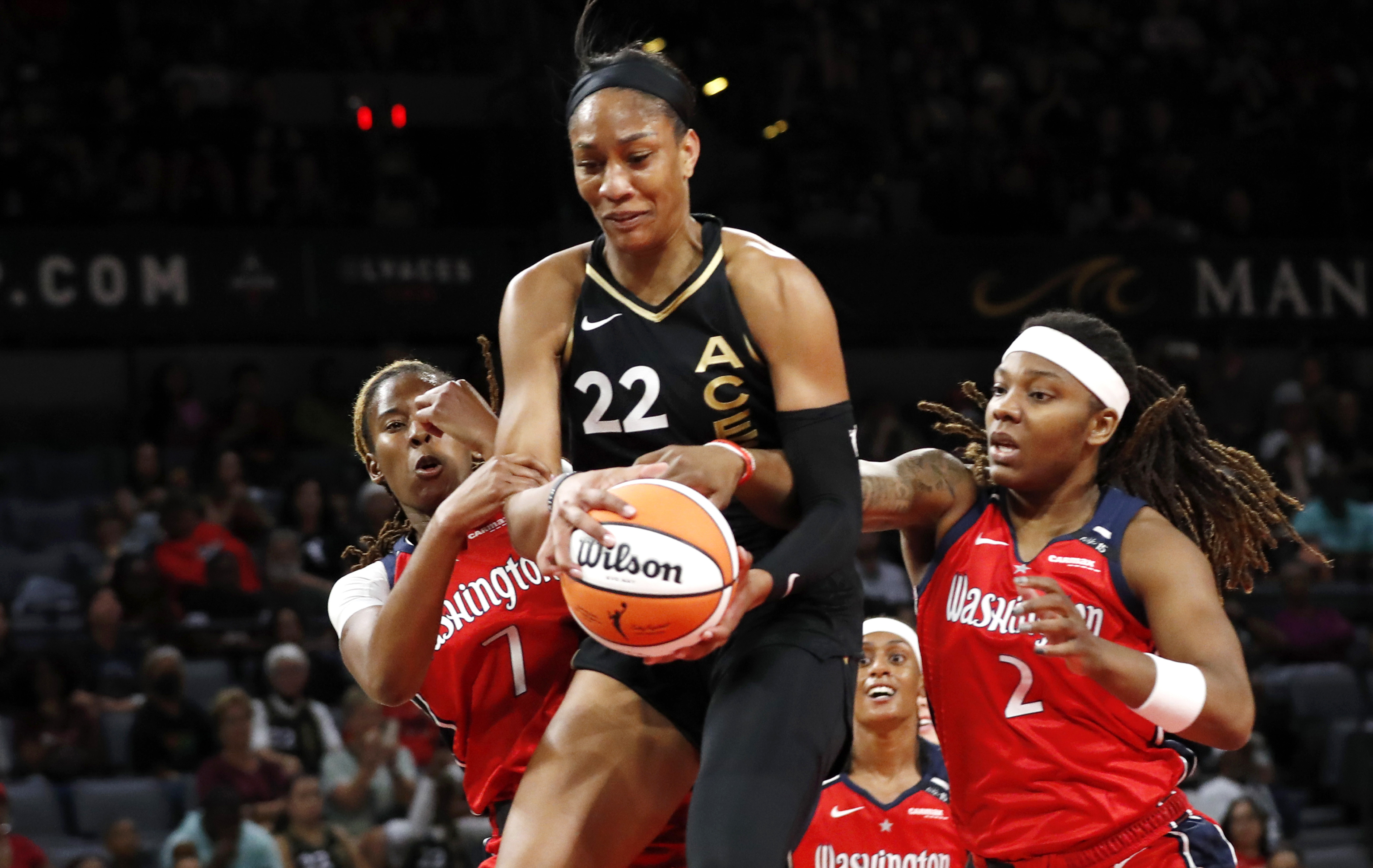 Las Vegas Aces forward A'ja Wilson (22) pulls down a rebound between Washington Mystics guard Ariel Atkins (7) and forward Myisha Hines-Allen (2) during the first half of a WNBA basketball game Thursday, Aug. 31, 2023, in Las Vegas.