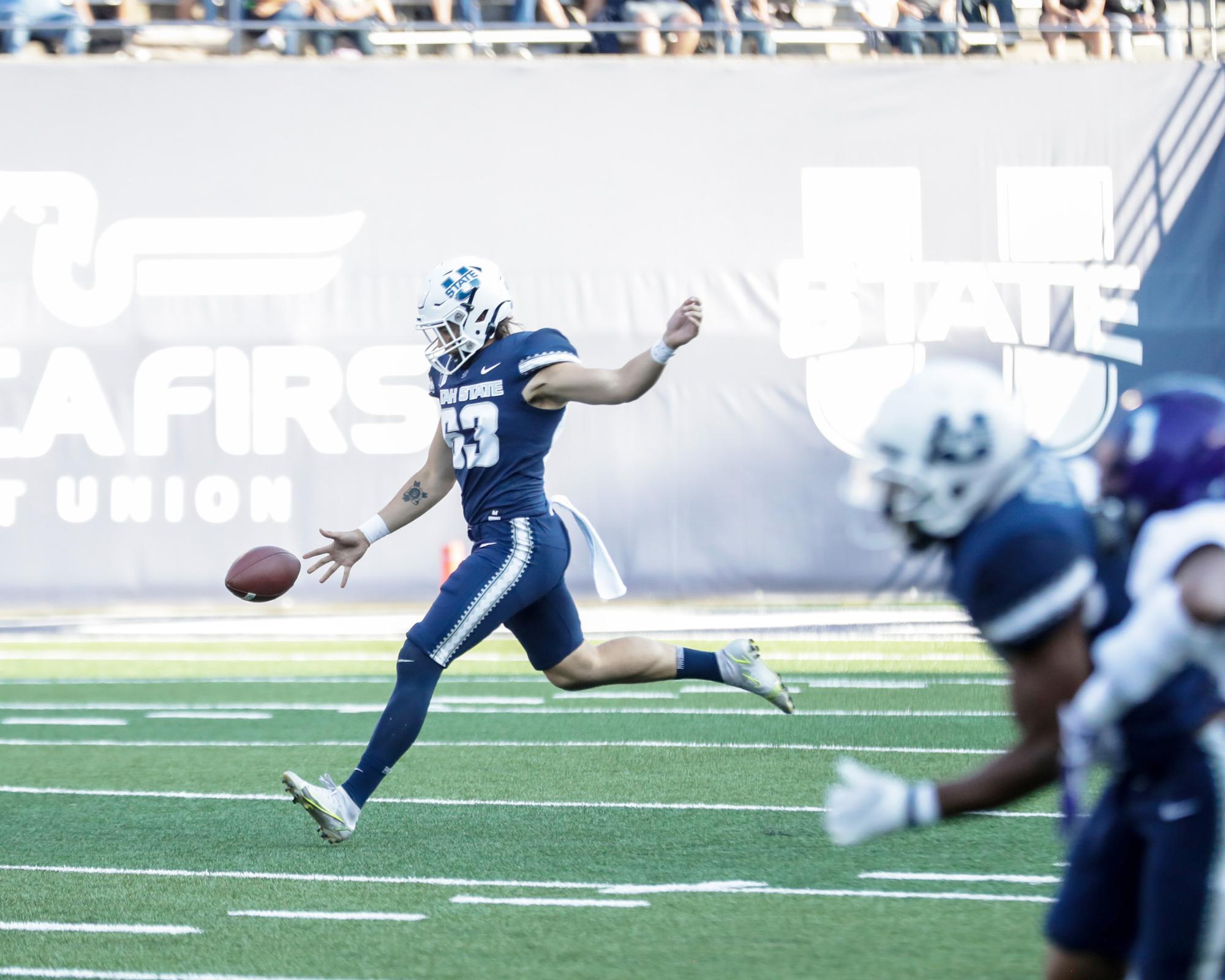 Kotsanlee punts a football at Maverik stadium during one of Utah State's football games.