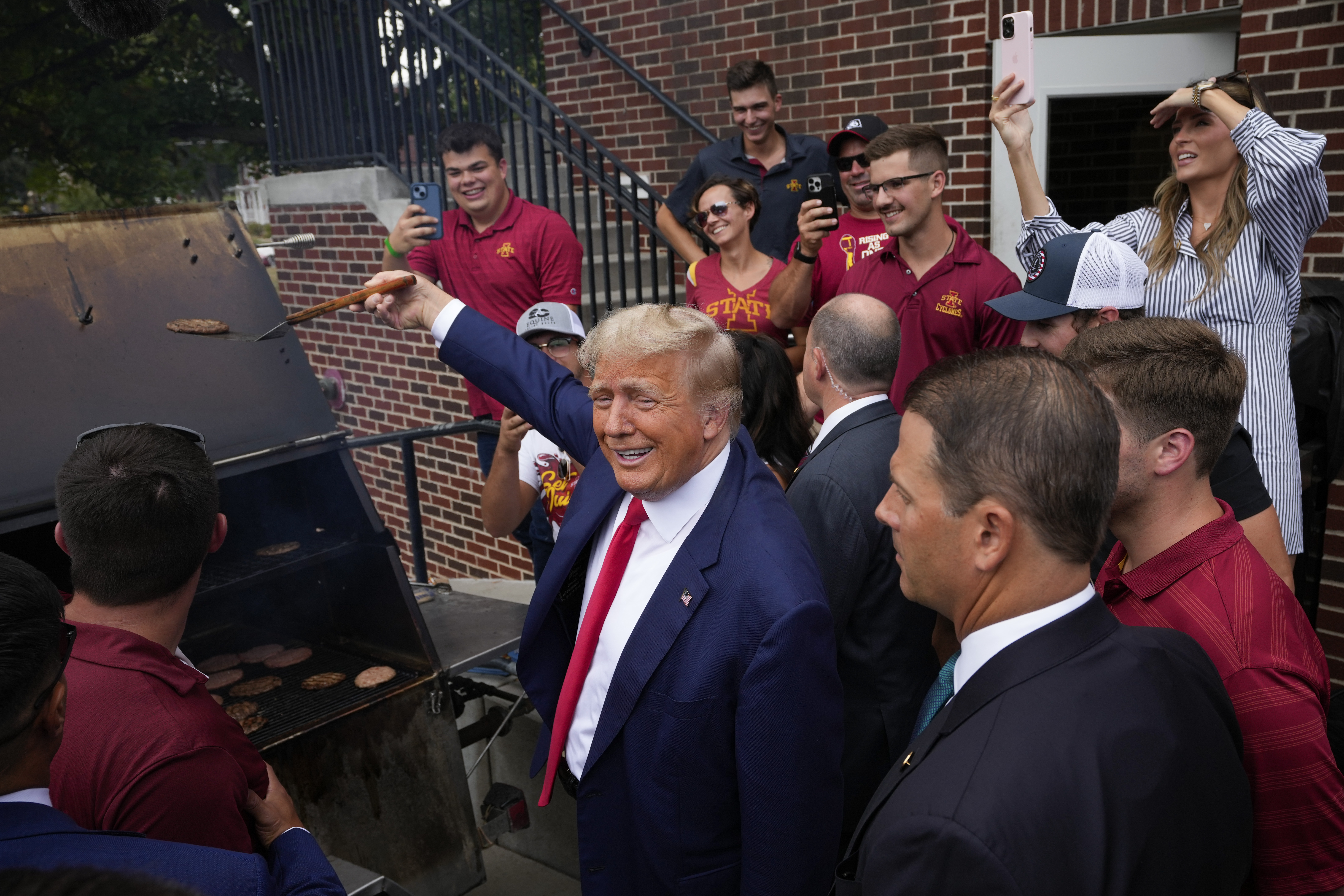 Former President Donald Trump works the grill during a stop at the Alpha Gamma Rho, agricultural fraternity, at Iowa State University before an NCAA college football game, Sept. 9 in Ames, Iowa. Former President Donald Trump is waiving his right to seek a speedy trial in a Georgia case.