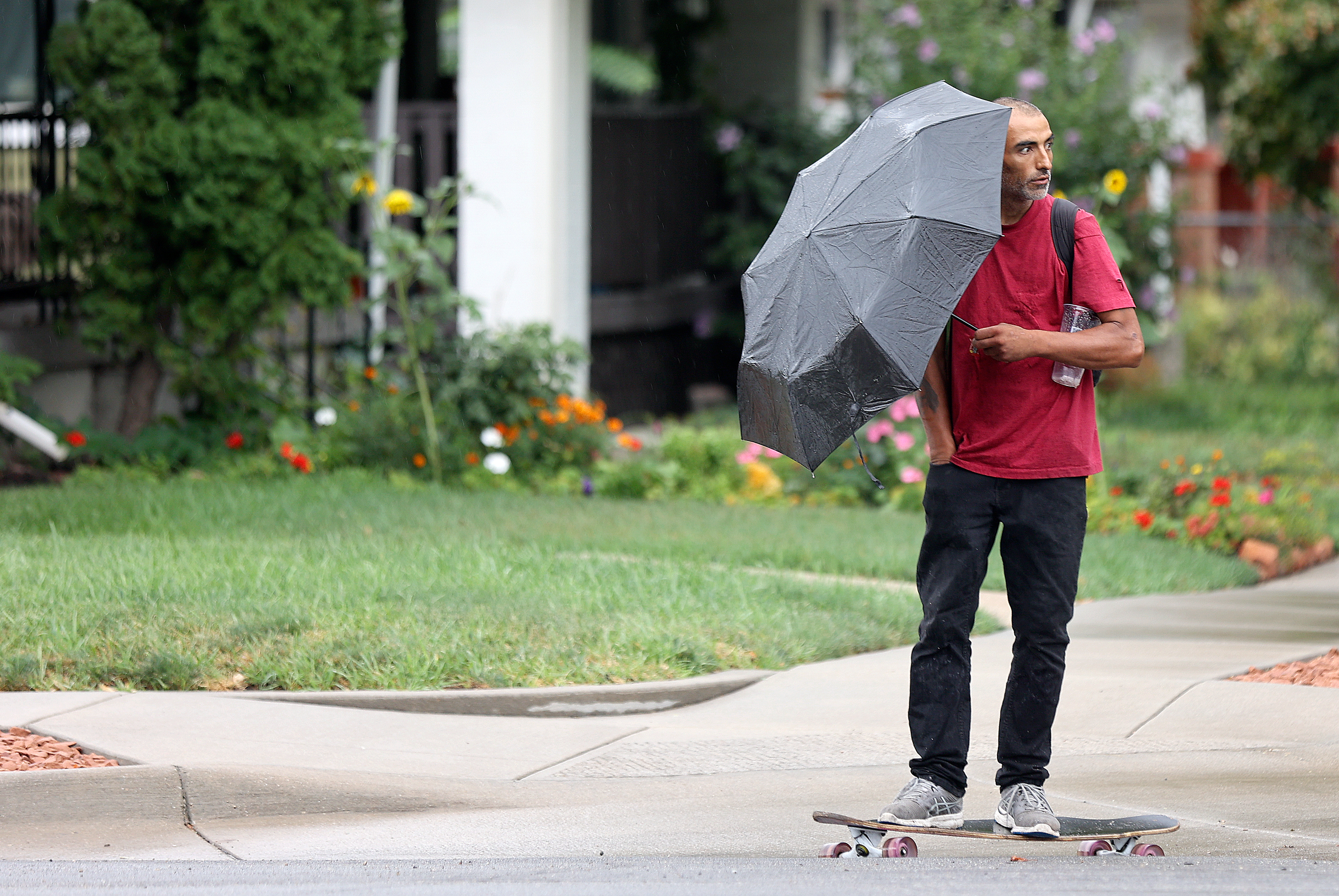 A man skateboards with an umbrella as it rains in Salt Lake City on Aug. 22. Utah water officials say recent monsoonal moisture provided some major benefits for the state's water supply.