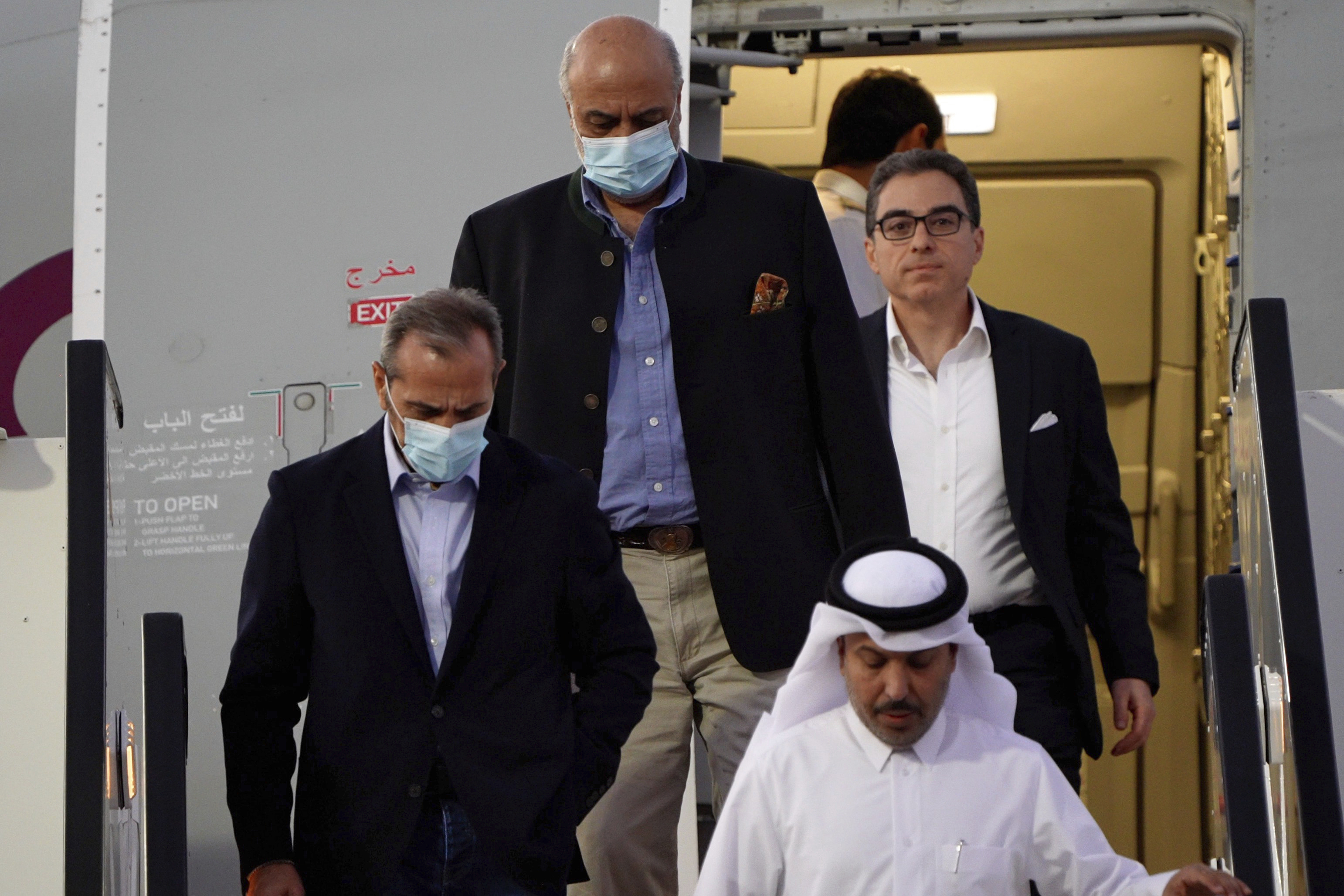 From left, Emad Sharghi, Morad Tahbaz and Siamak Namazi, former prisoners in Iran, walk out of a Qatar Airways flight that brought them out of Tehran and to Doha, Qatar, Monday. Five prisoners sought by the U.S. in a swap with Iran were freed Monday and headed home as part of a deal that saw nearly $6 billion in Iranian assets unfrozen.