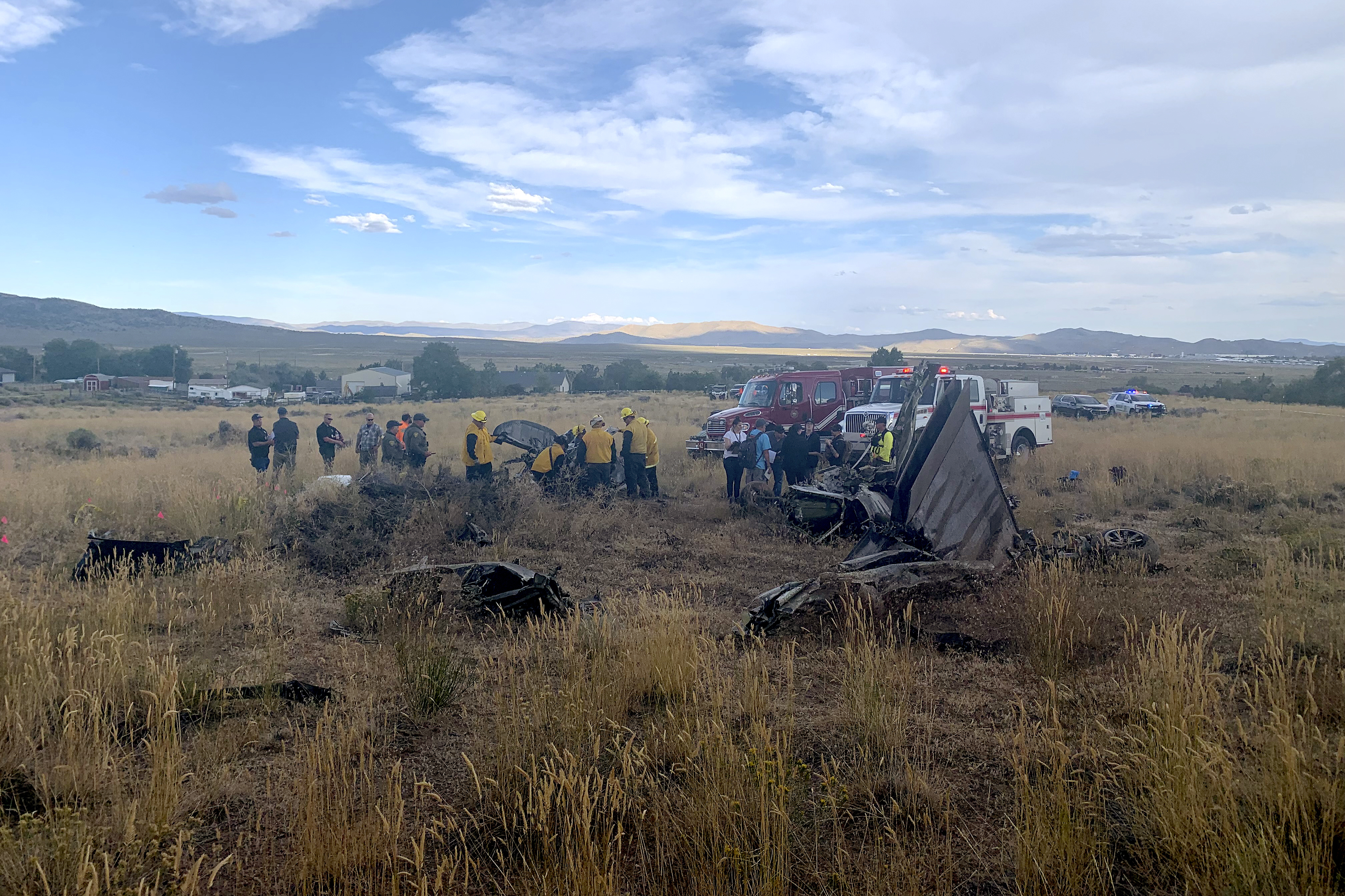 In this photo provided by the Truckee, Calif., Meadows Fire and Rescue Department, members of the Truckee Meadows Fire and Rescue Department and other officials look over aircraft wreckage, Sunday, Sept. 17, 2023, in Reno, Nev., after two California pilots were killed when their planes collided in mid-air while preparing to land after completing a race at the National Championship Air Races north of Reno. 