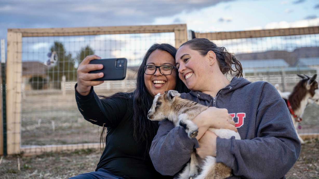 Attendees take a selfie with a baby goat during Goat Yoga at Inner Peas Farm in Hurricane, Utah.