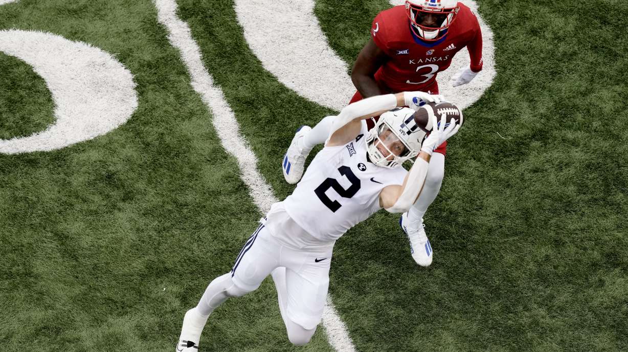 BYU wide receiver Chase Roberts (2) catches a pass under pressure from Kansas cornerback Mello Dotson (3) during the first half of an NCAA college football game Saturday, Sept. 23, 2023, in Lawrence, Kan.