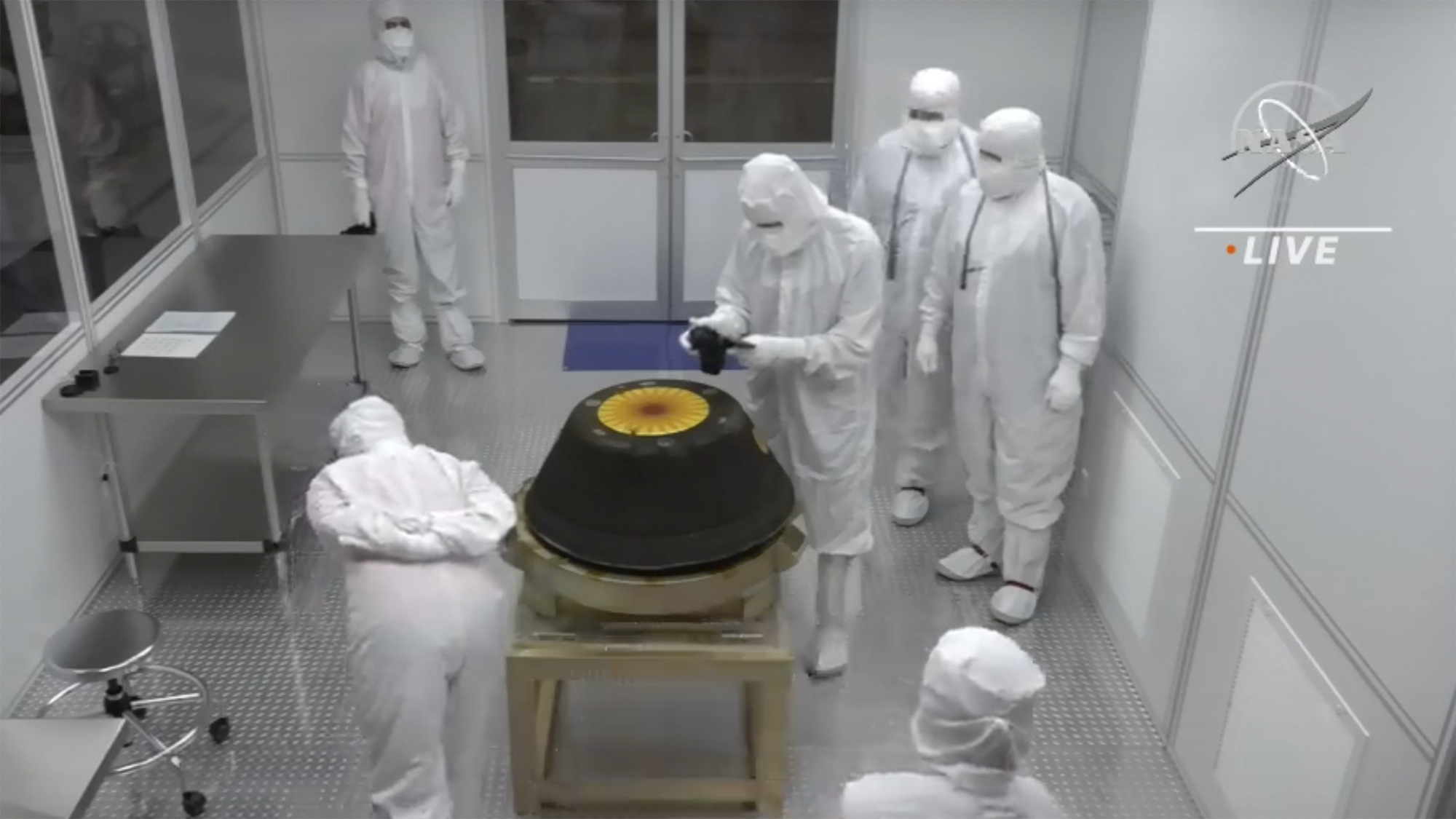 In this image from video provided by NASA, technicians in a clean room examine the sample return capsule from NASA's Osiris-Rex mission after it landed at the Department of Defense's Utah Test and Training Range on Sunday. The sample was collected from the asteroid Bennu in October 2020.