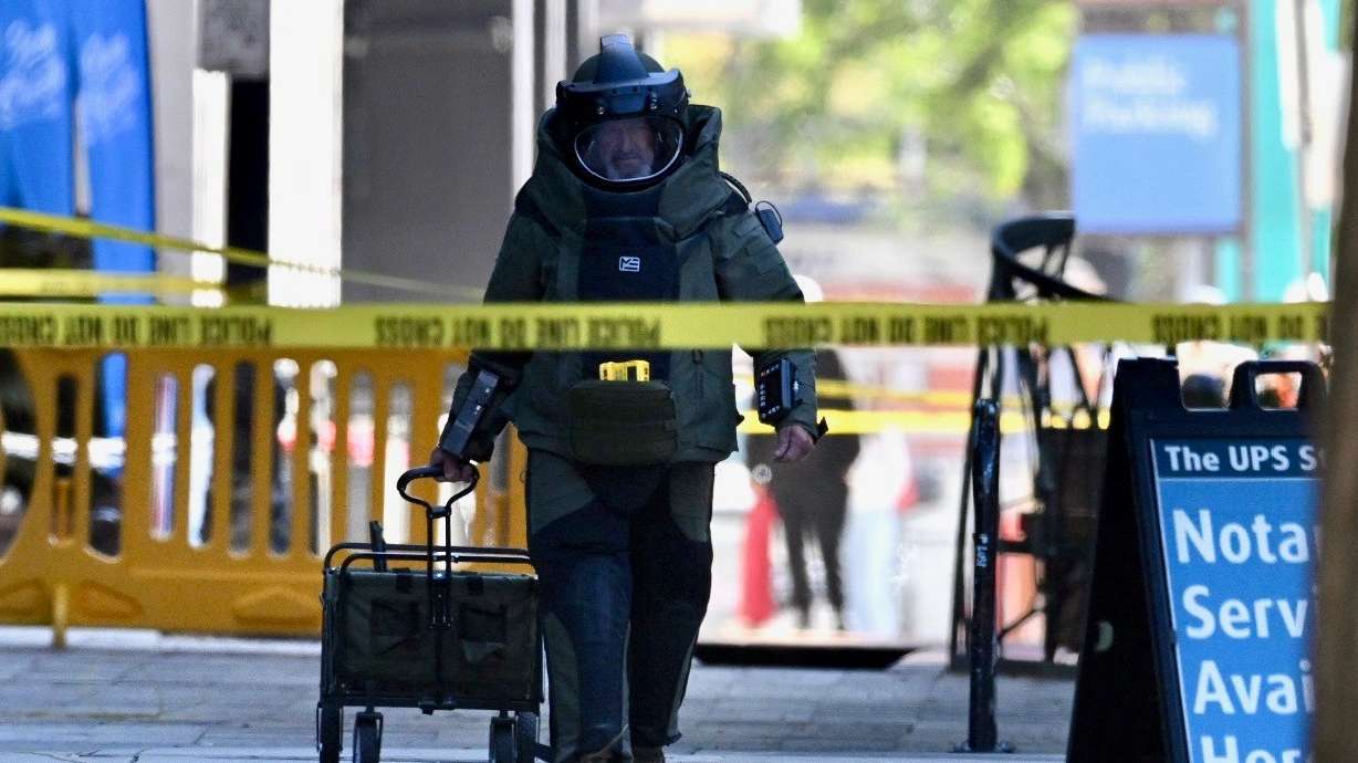 A man in a bomb suit returns from the area of a suspicious package or item at 200 South between Main and South Temple in Salt Lake City on Monday. After evacuations and closures, police later said the item was not a threat.