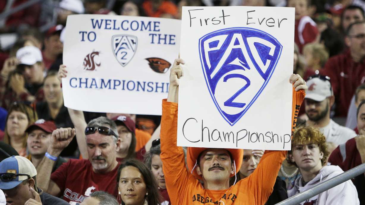 An Oregon State fan, front, and a Washington State fan hold "Pac-2" signs, representing the two schools that will remain in the Pac-12 after the 2023-2024 academic year after the other schools in the conference announced plans to leave, during the second half of an NCAA college football game, Saturday, Sept. 23, 2023, in Pullman, Wash.