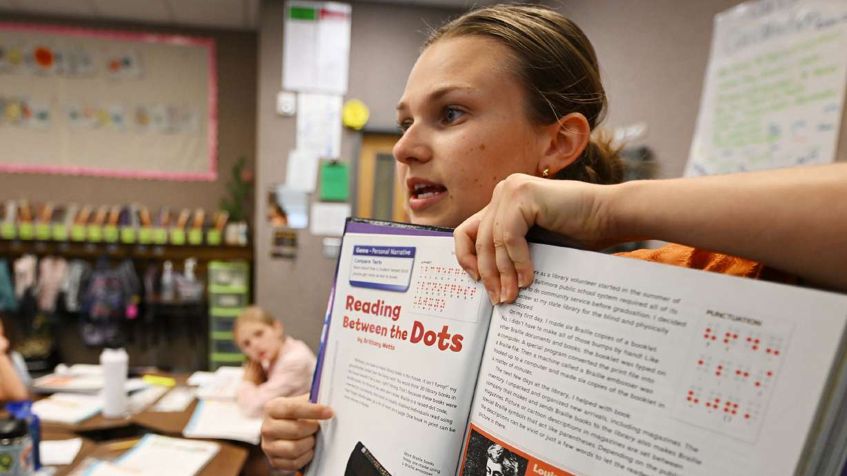 First-year teacher Margaret “Maggie” Johnston holds up a workbook as she works with her students at Crescent Elementary School in Sandy on Sept. 19. Eight Utah school districts are paying licensed first-year teachers $60,000 annually to start.