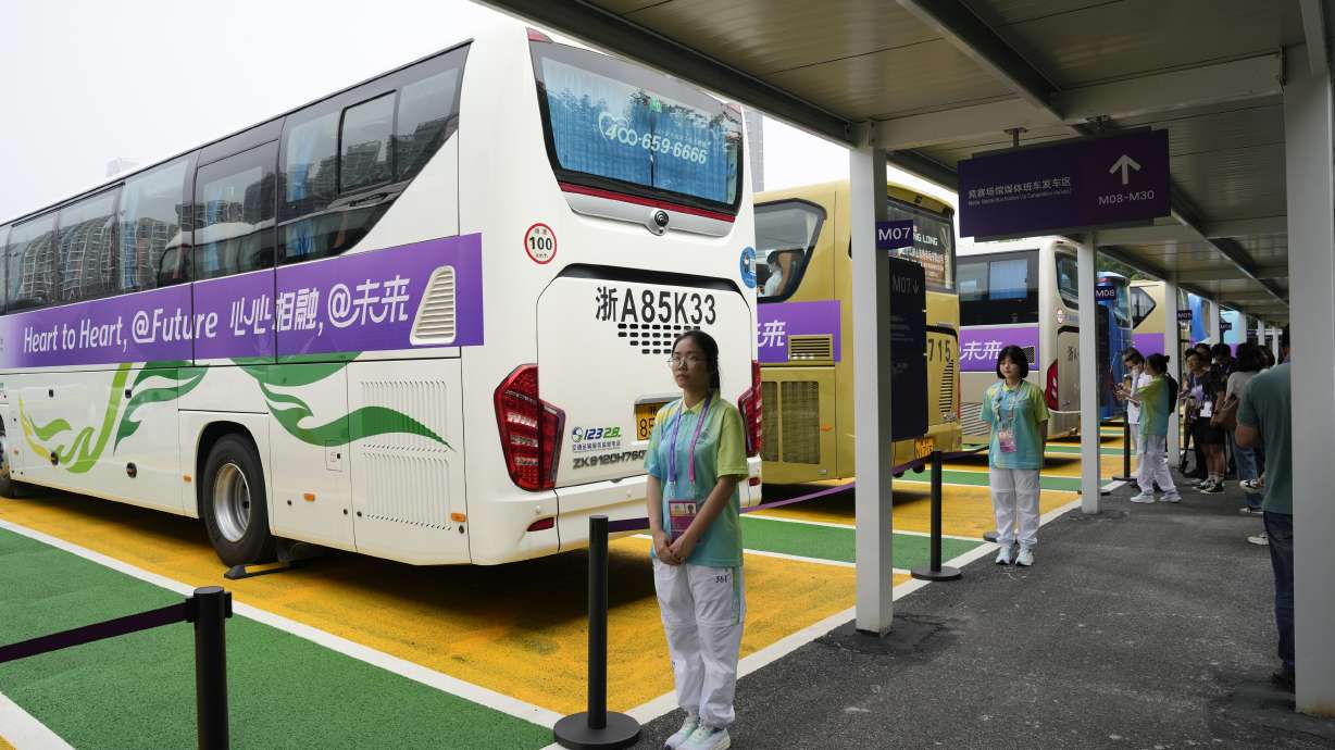 Chinese volunteers stand at a shuttle bus hub at the 19th Asian Games in Hangzhou, China, Tuesday, Sept. 26, 2023. Signs around Hangzhou billed the city as a "paradise on earth" while China adopted the motto "heart to heart" for the games, which attract feature some 12,000 competitors, more than the summer Olympics, from across Asia and the Middle East.