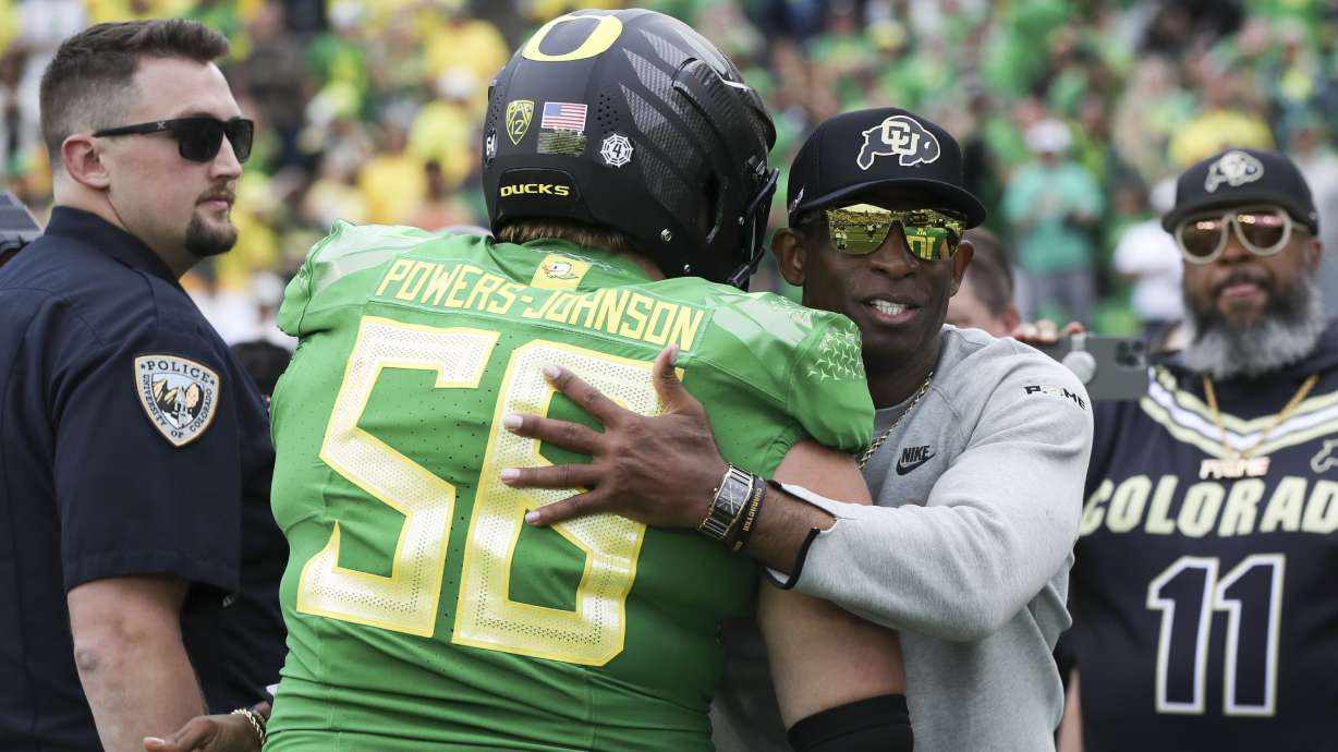 Colorado head coach Deion Sanders hugs Oregon offensive lineman Jackson Powers-Johnson following an NCAA college football game, Saturday, Sept. 23, 2023, in Eugene, Ore. Oregon won 42-6.