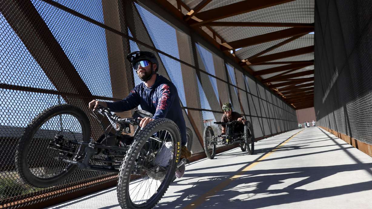 Hand cyclists pedal across a bridge over the Jordan River section of Parley's Trail in West Valley City on Thursday. The primarily elevated section of Parley's Trail, from 900 West to Jordan River Parkway, is complete and officially open to the public.