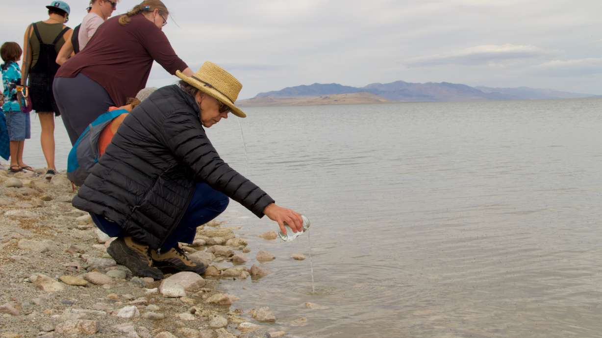 Individuals pour jars of water into the Great Salt Lake during an offering ceremony to the lake on Saturday at Antelope Island State Park.