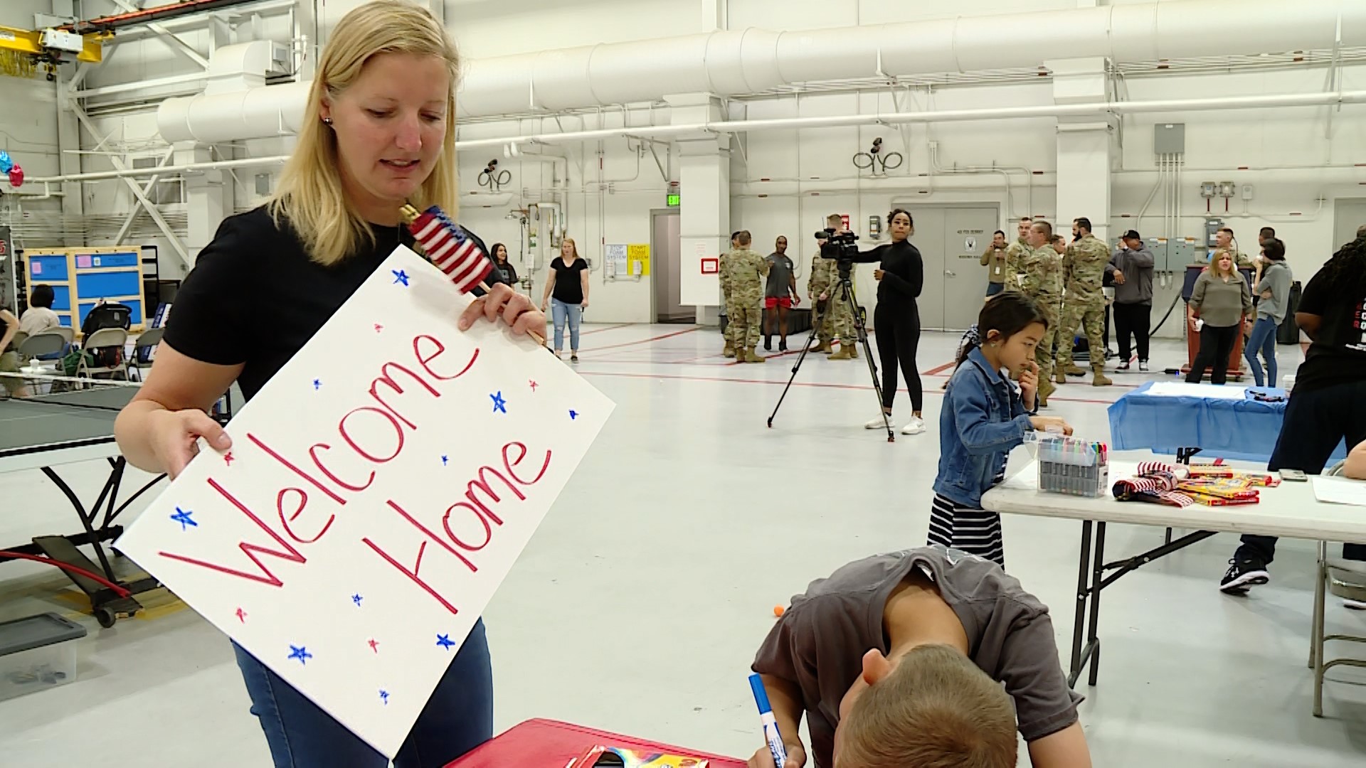Ashley Schoolcraft helping her son, Adam, create “welcome home” signs at Hill Air Force Base Saturday.